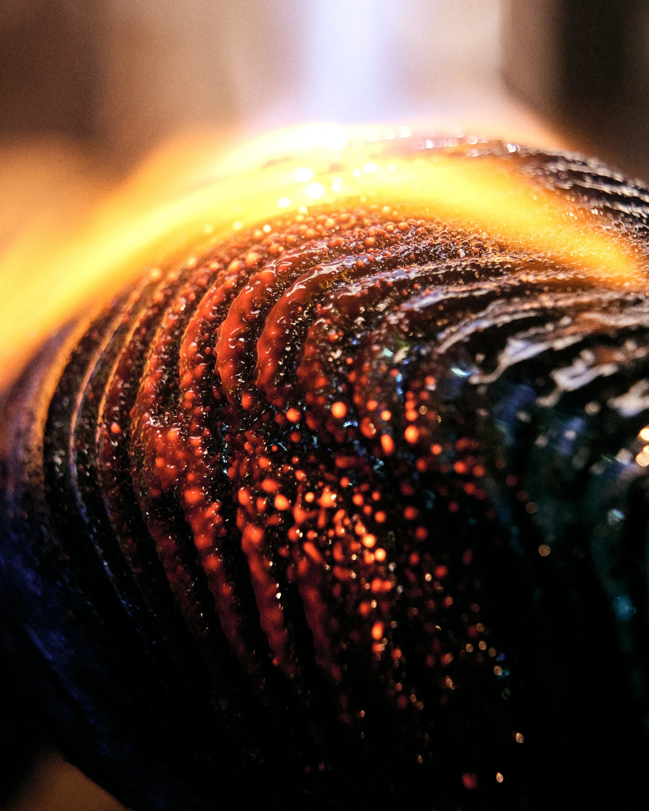 Close-up of a dark, glossy, textured object with orange highlights, possibly a sculpture or abstract art piece.
