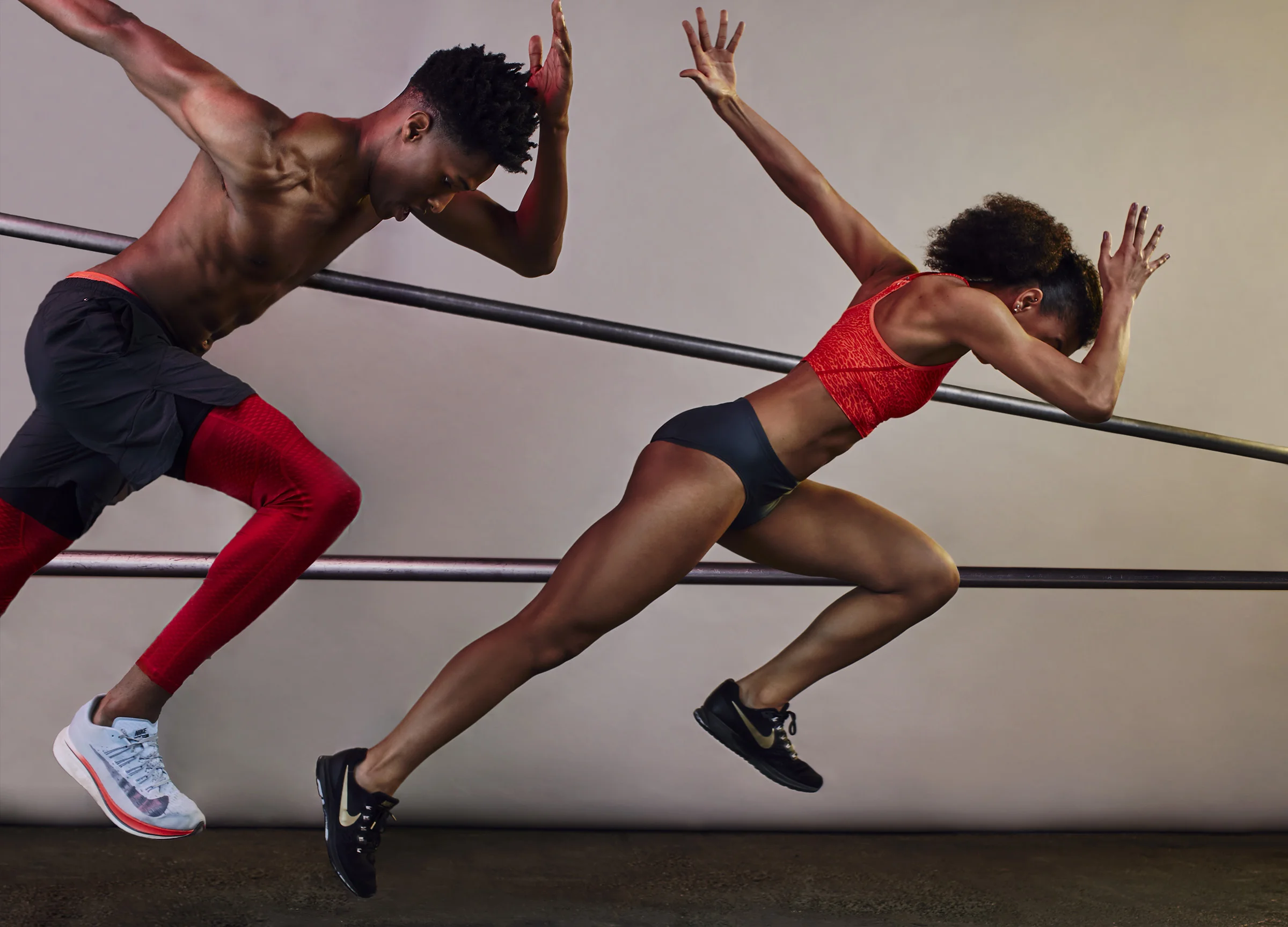 An athlete woman and a male athlete man in sportswear running on a track and pushing against a railing, captured in motion.