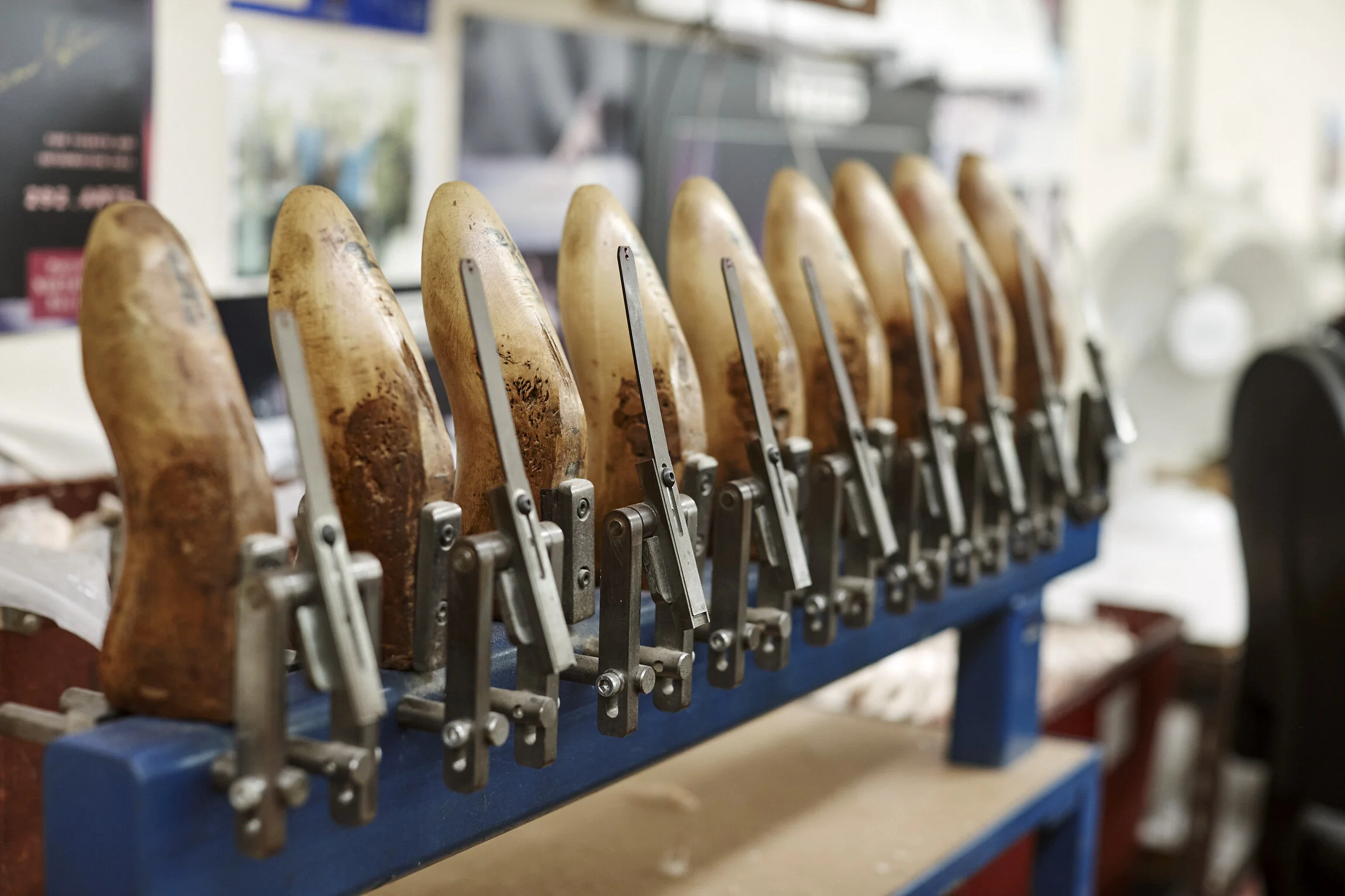 A row of wooden shoetrees with metal clamps in a shoe store display