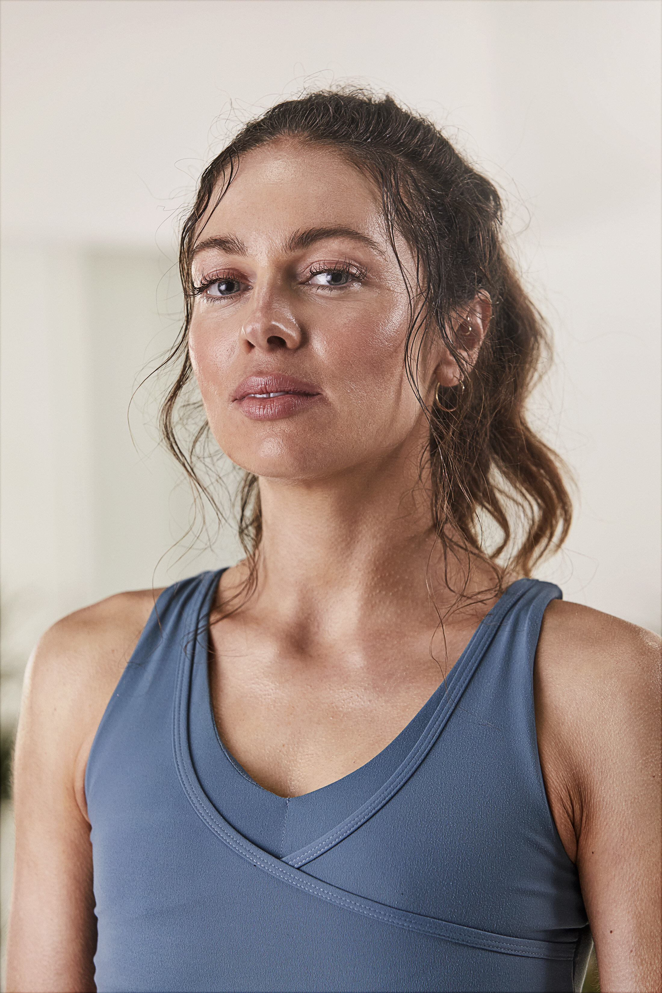 A woman with wet, curly brown hair wearing a blue athletic top.
