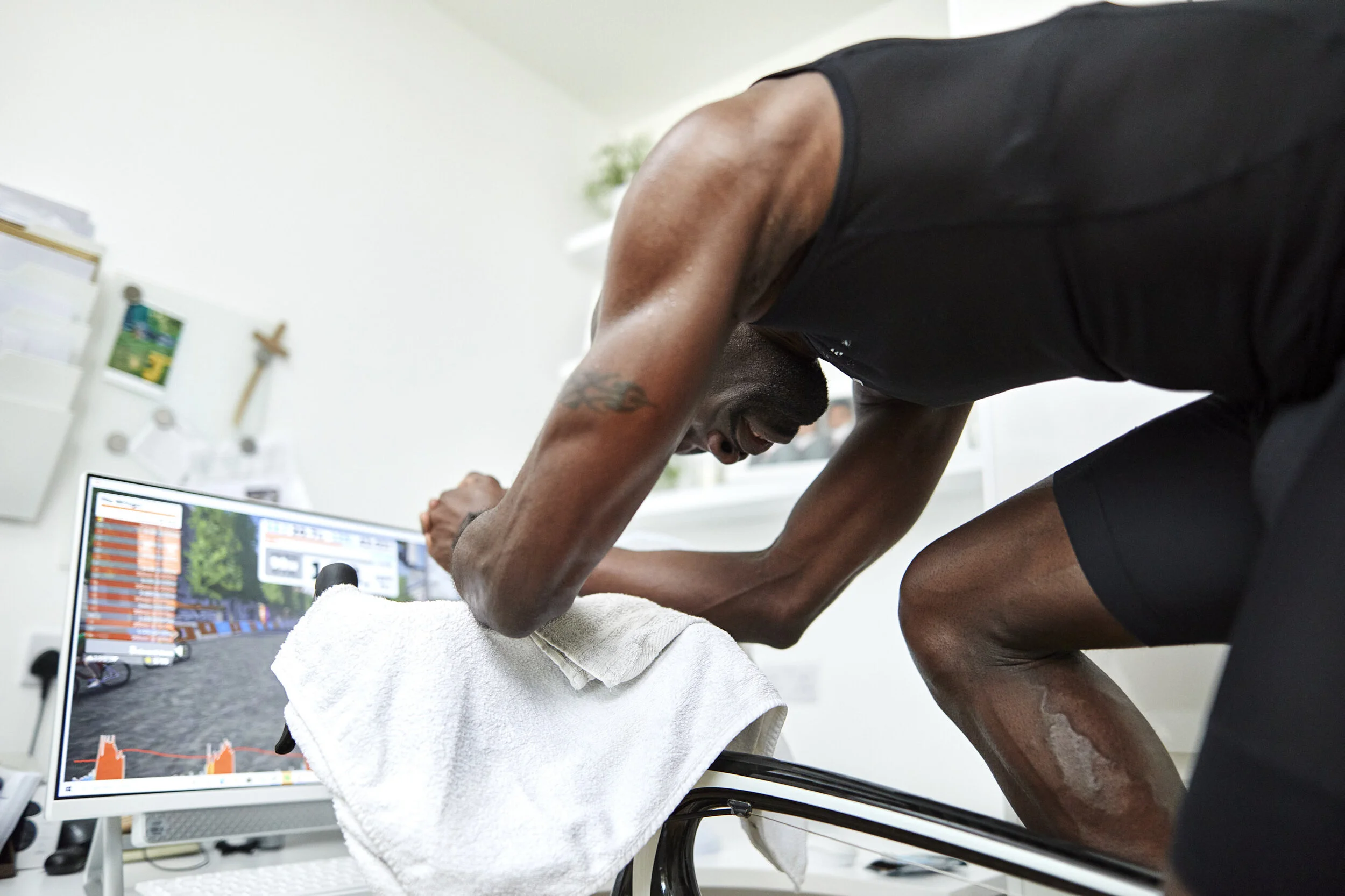 A man doing physical therapy exercises on a treadmill in a clinical setting, with a monitor displaying a graph and outdoor scenery