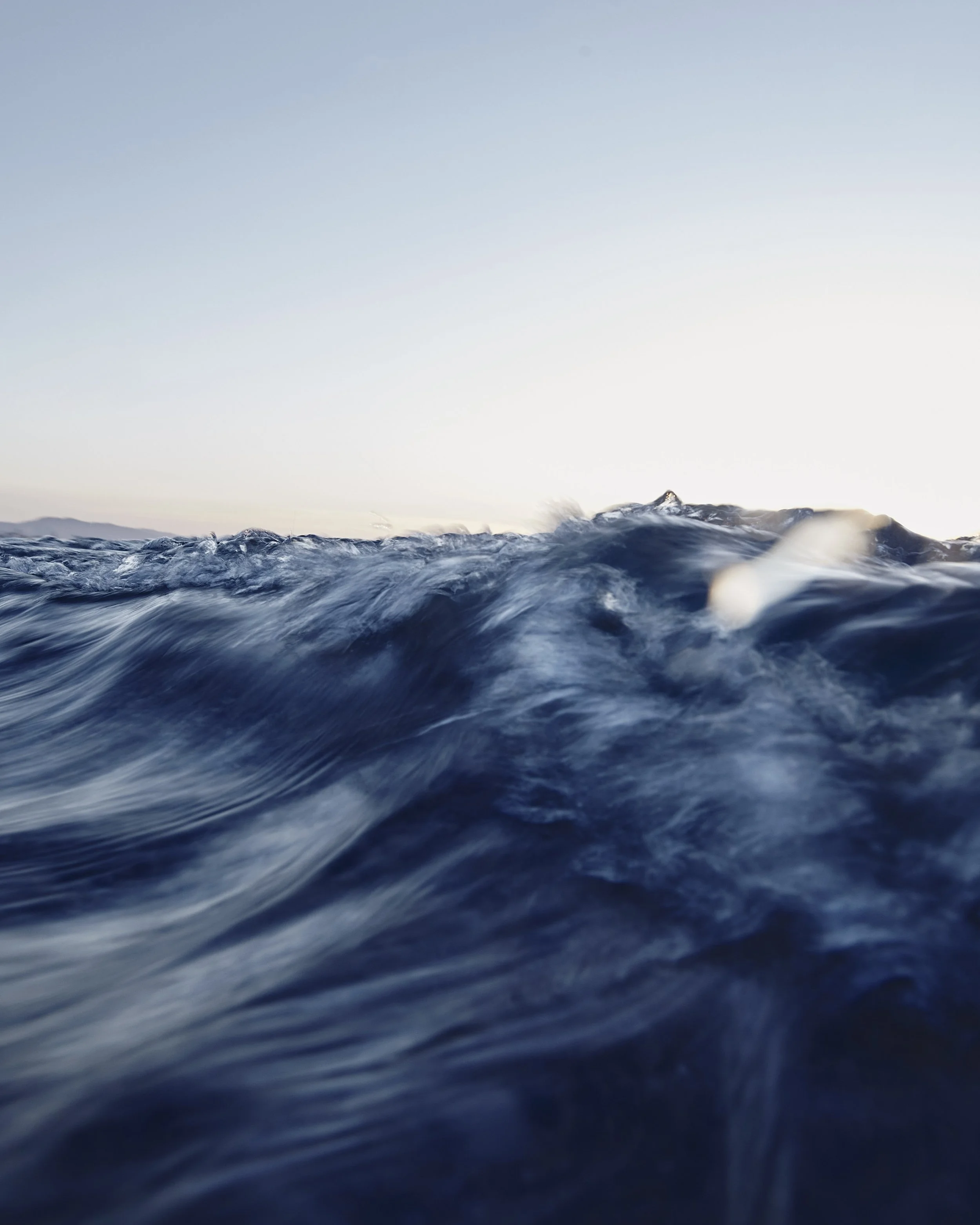 Ocean waves with a clear sky in the background, taken from a low angle.