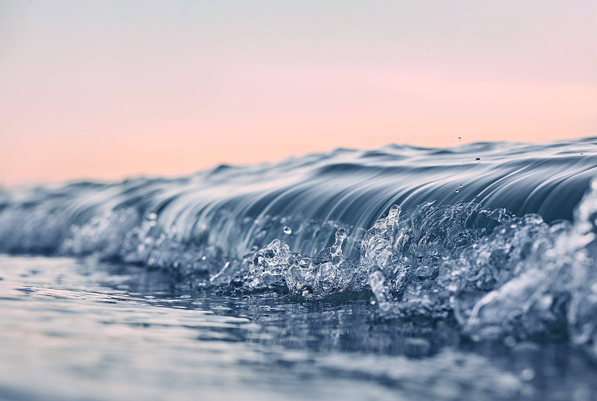 Close-up of ocean waves with pink and blue sky in the background.