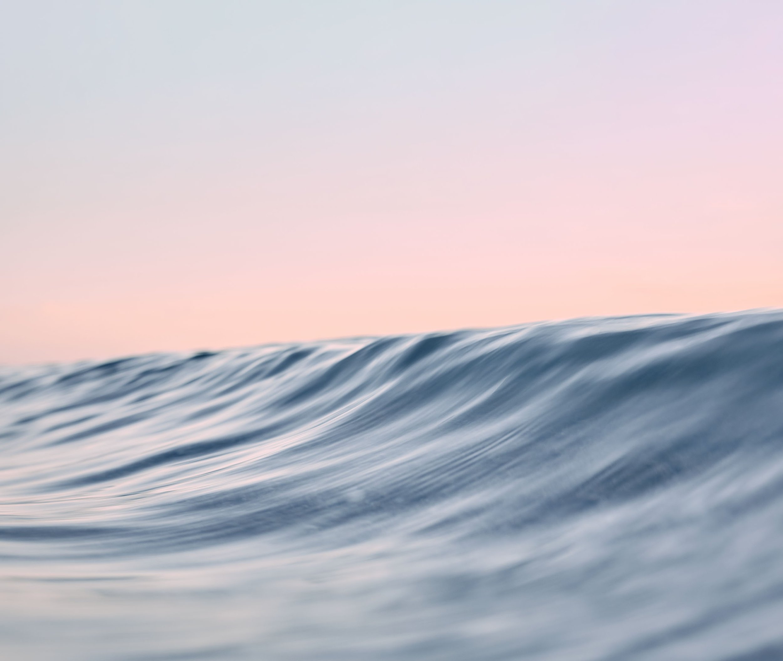 Close-up of ocean waves with a pastel sky in the background.