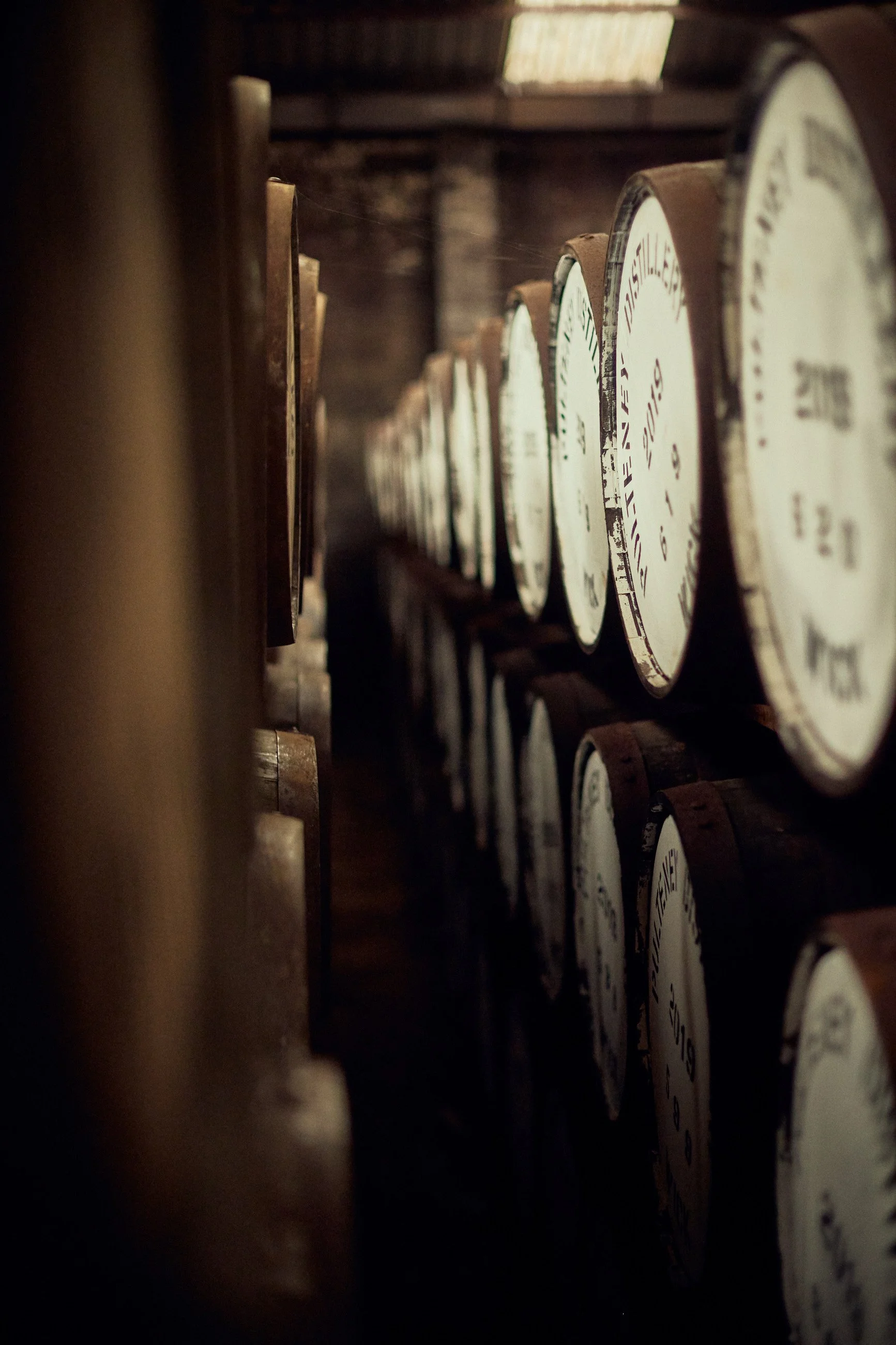 A stack of large, vintage clocks with white faces and dark frames, stored in a wooden shed or barn with dim lighting.