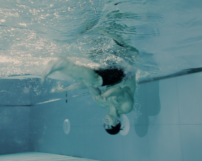 Swimmer in a pool performing a flip underwater