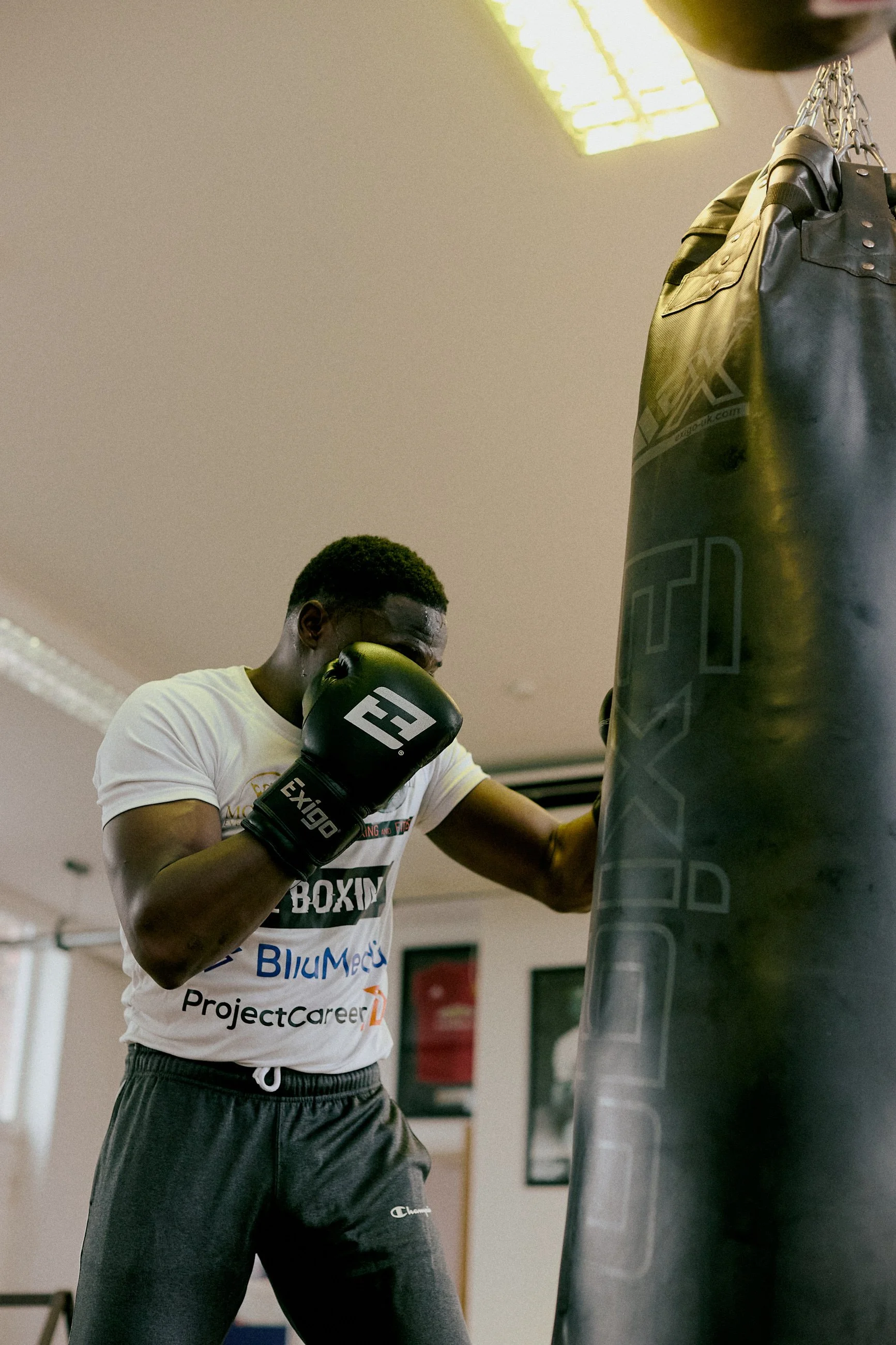 A person wearing boxing gloves training on a punching bag in a gym.