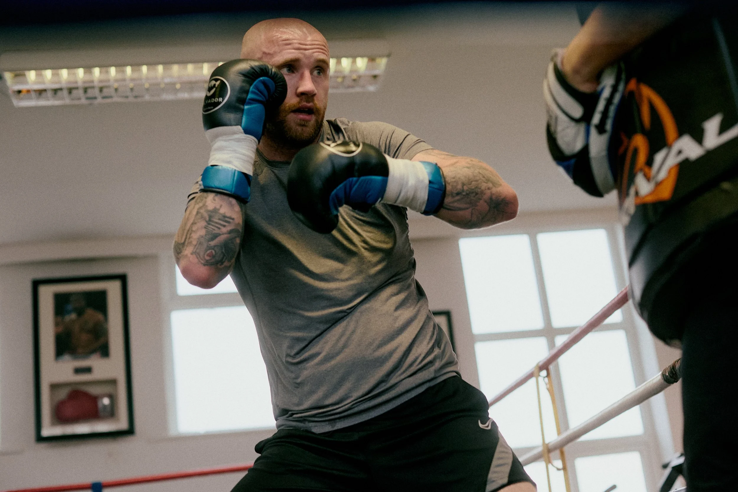 A boxer in gloves practicing punches during training in a gym.