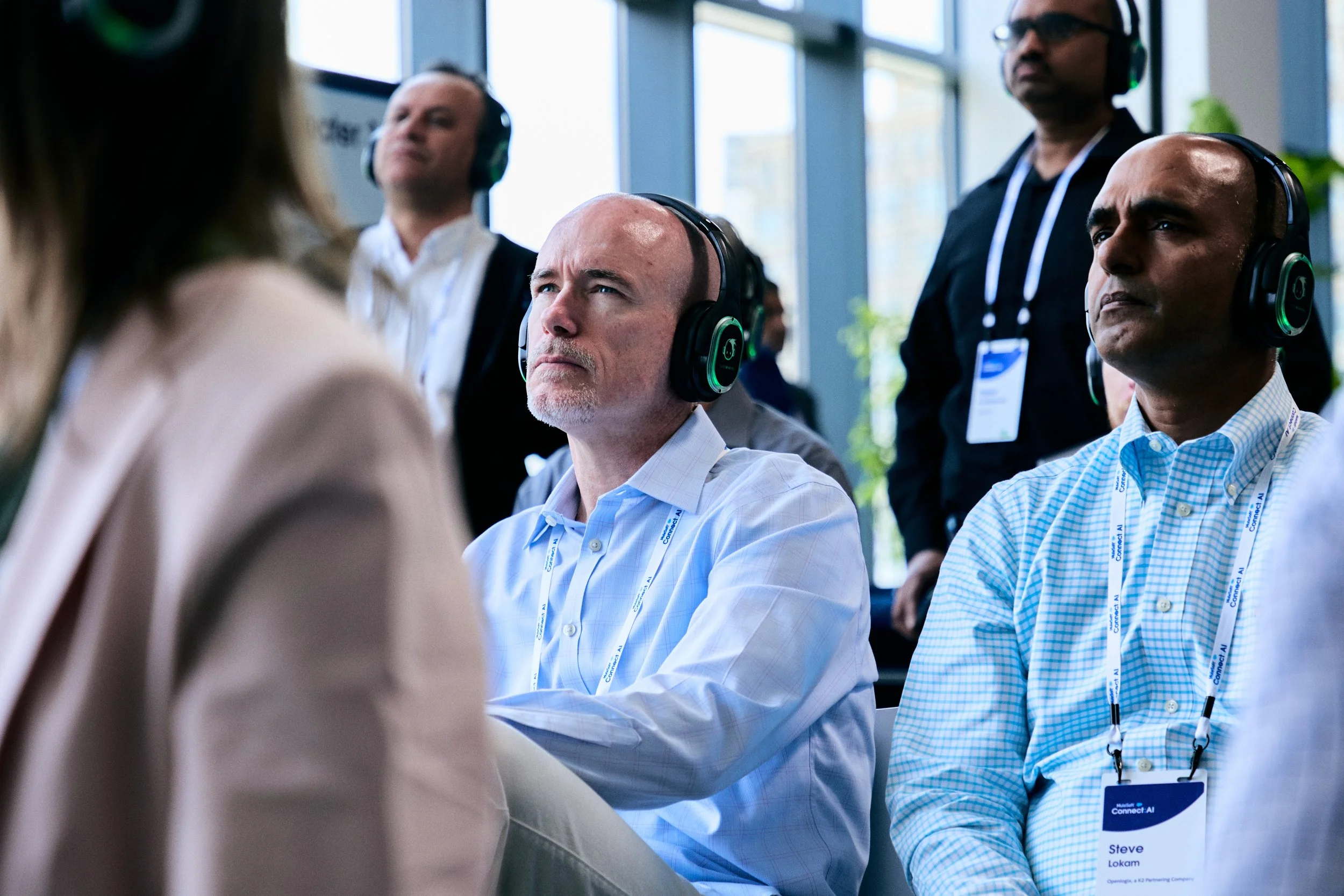Three men with headphones listening attentively during a conference.