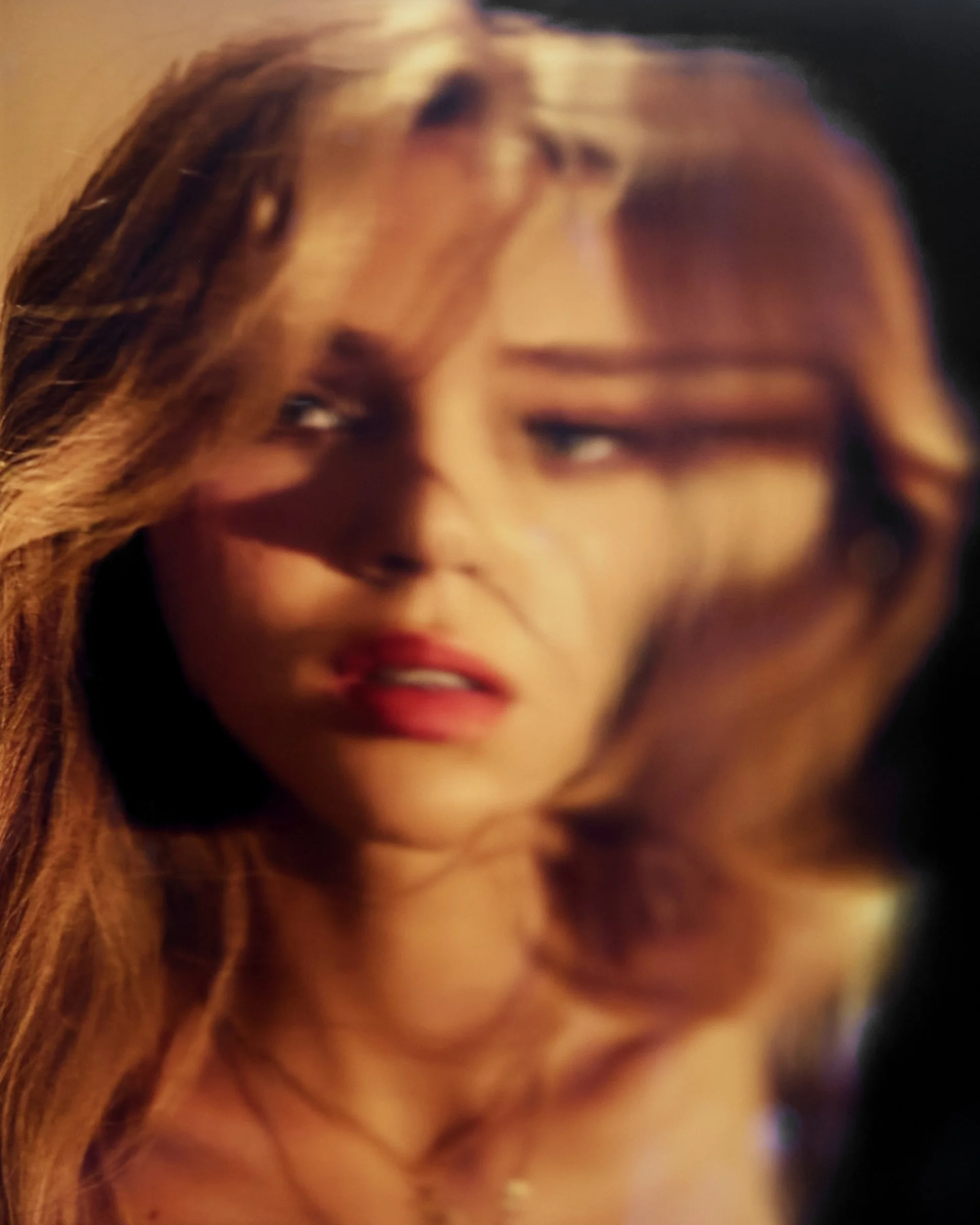 Close-up of a woman with long, wavy hair, looking anxious or concerned, with a shadow cast across part of her face.