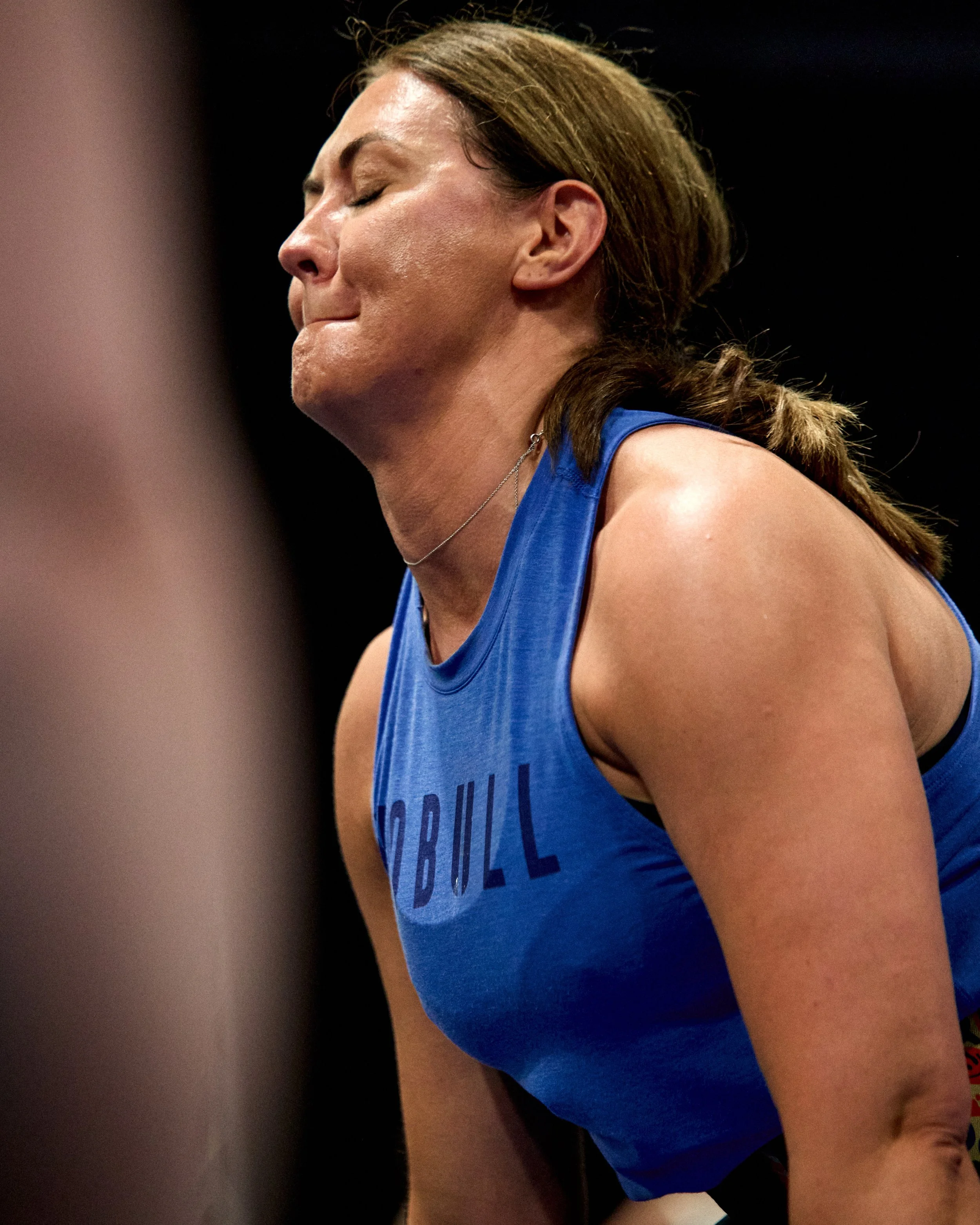 Close-up of a woman in workout attire, with her eyes closed and a focused expression.