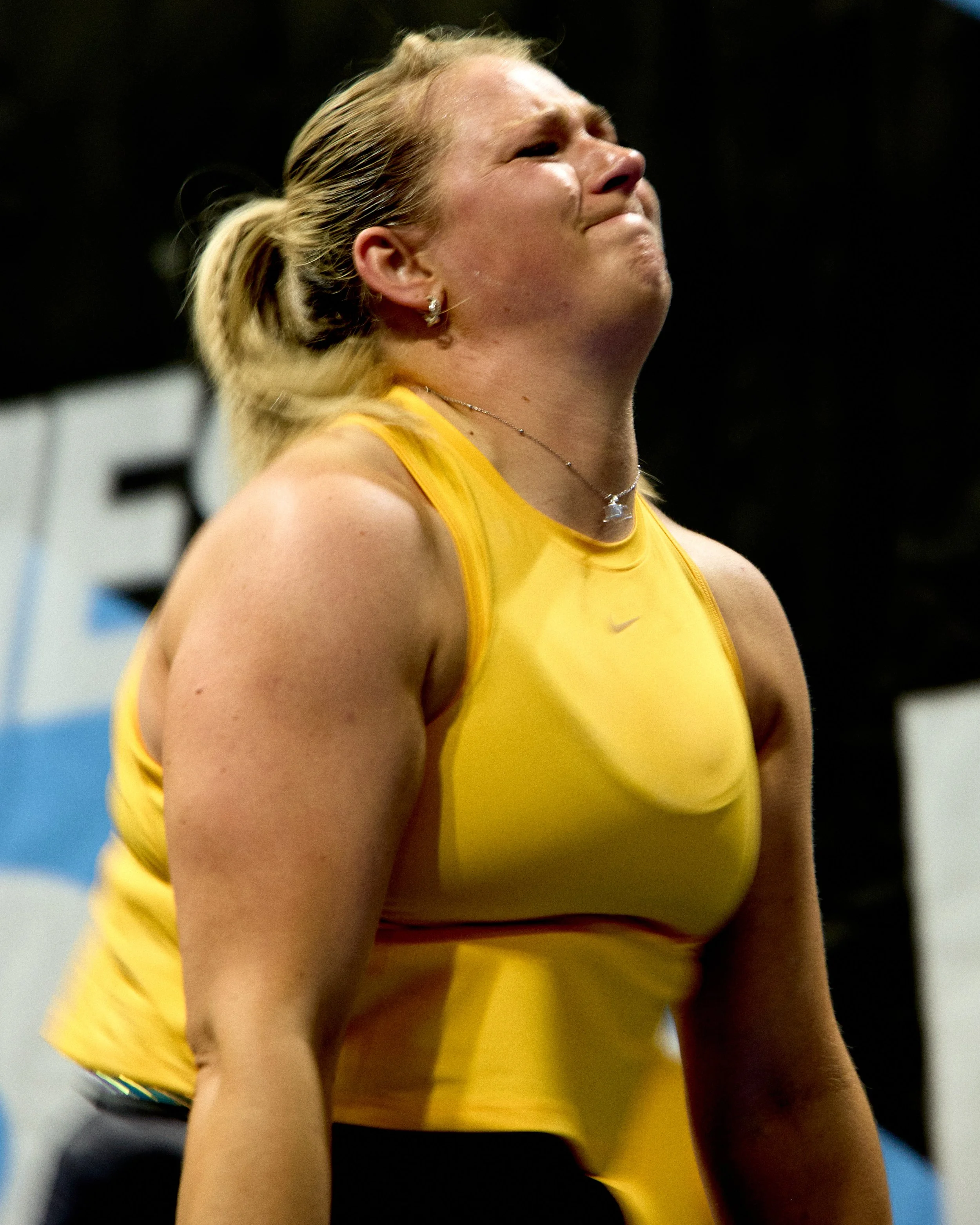 A female athlete in a yellow sports top appears to be crying or upset, with her eyes closed and face scrunched.