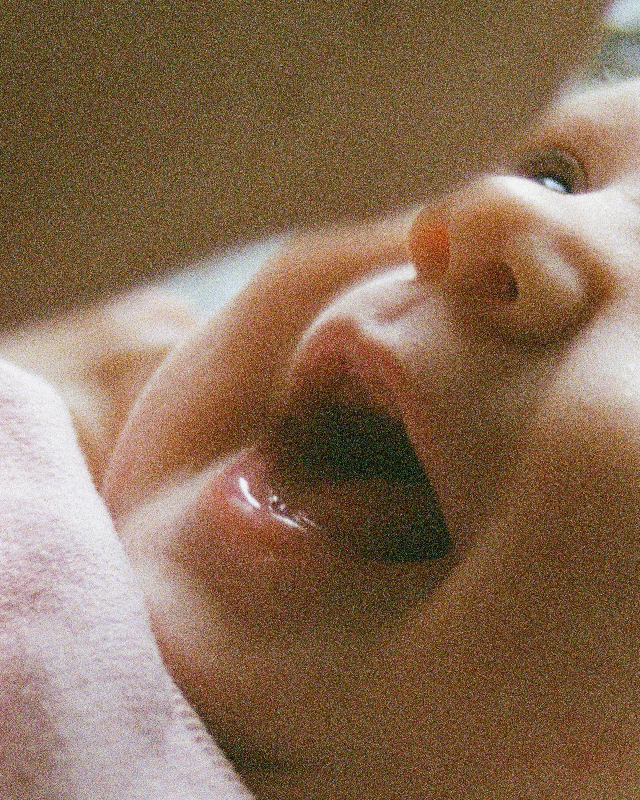 Close-up of a baby's face with mouth open and tongue sticking out, showing part of the nose and one eye.