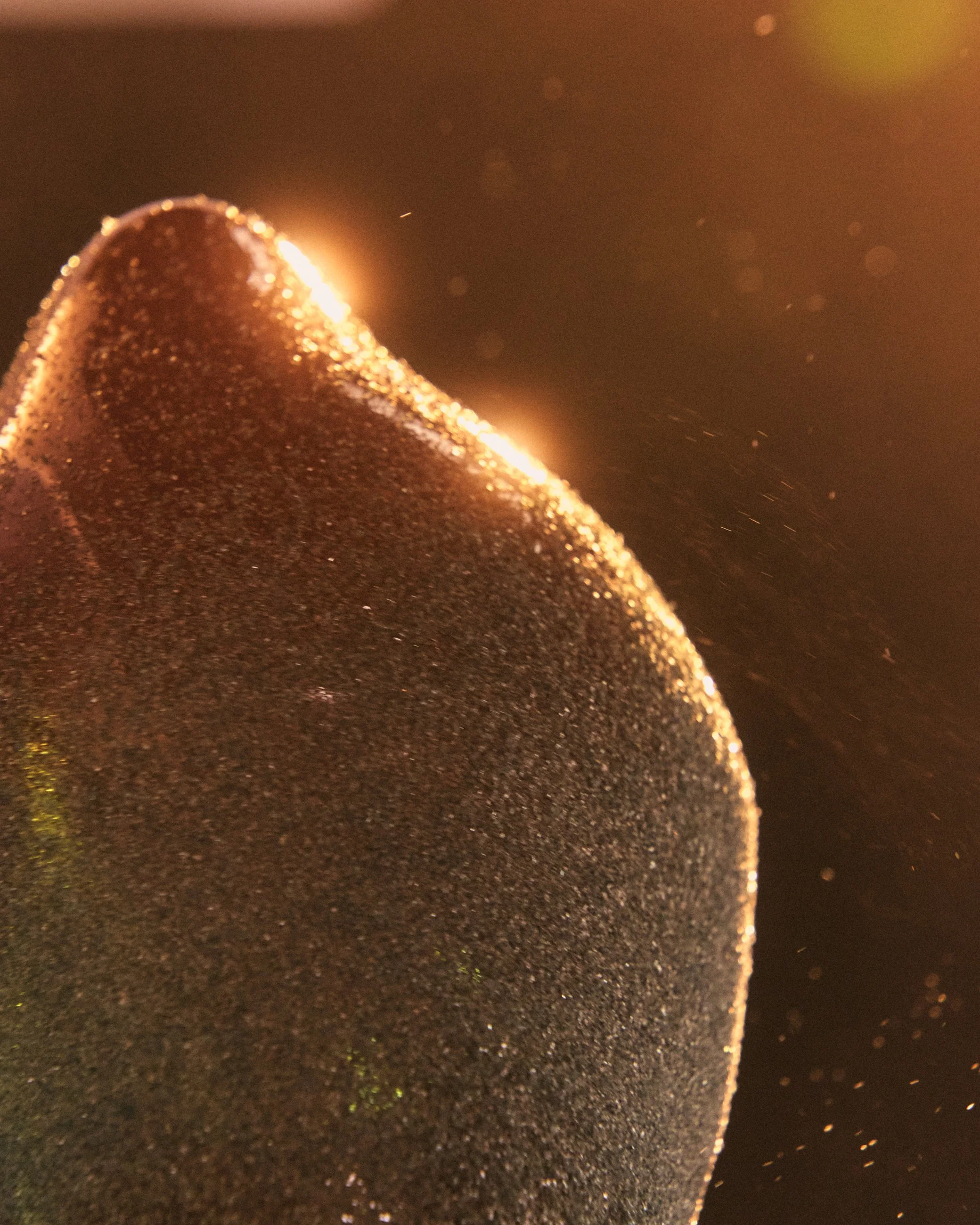 Close-up of a dark brown object with a shiny, glittery surface and a rounded shape.