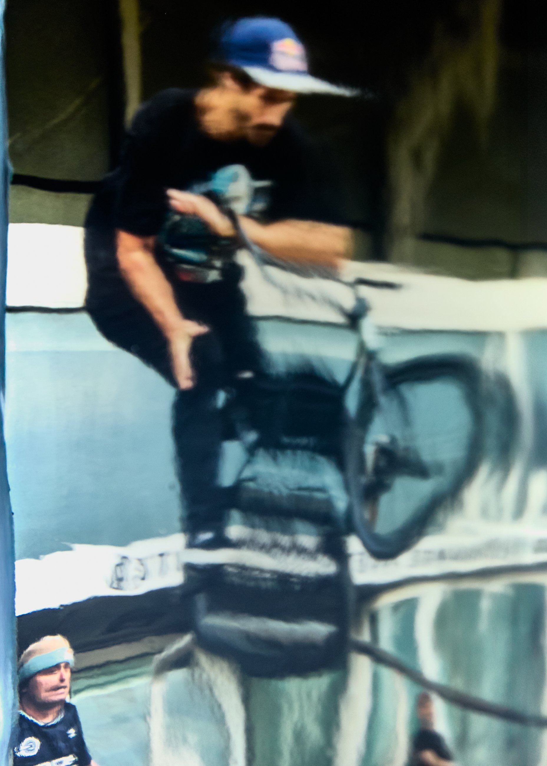 A person wearing a cap and black t-shirt riding a bicycle.