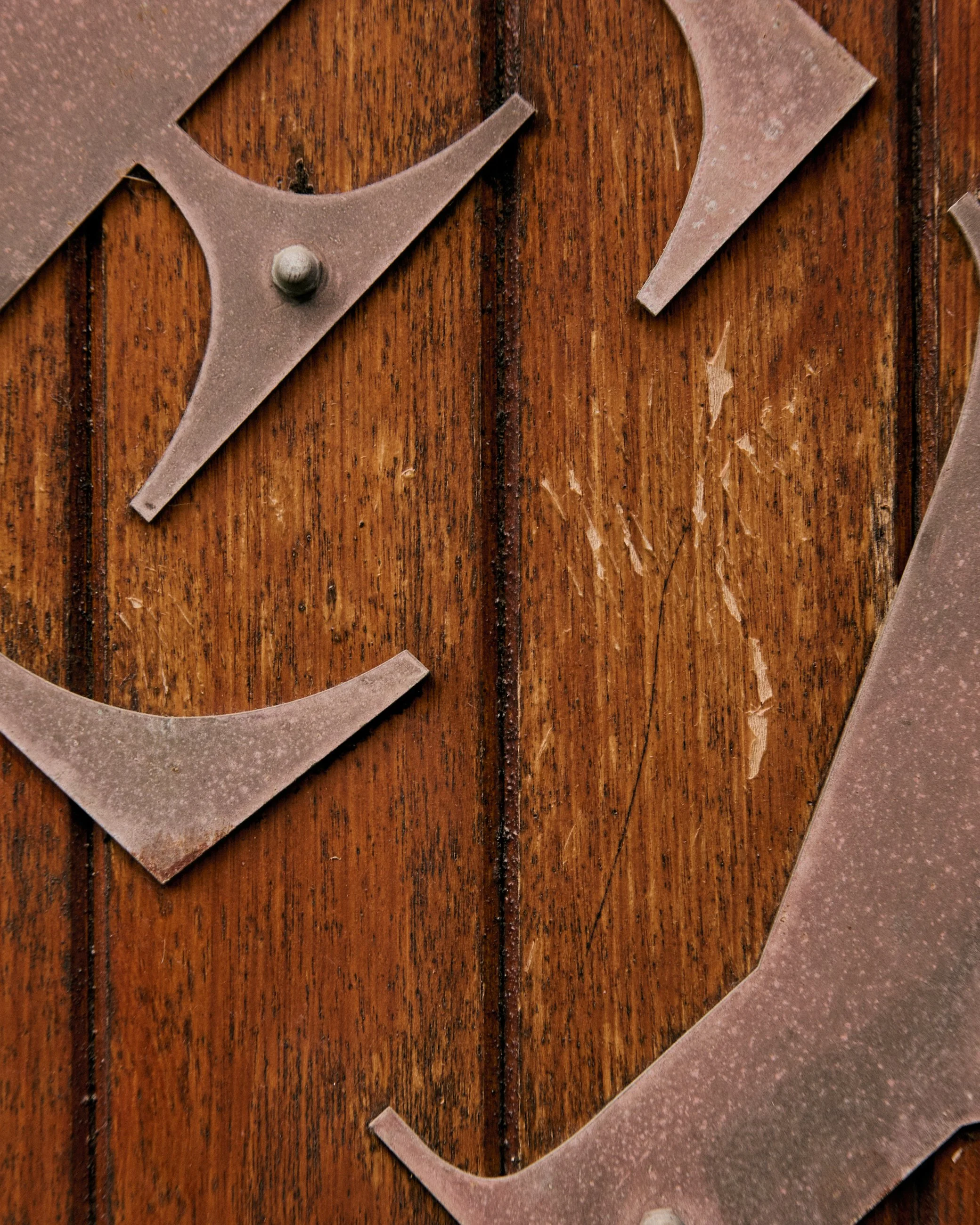 Close-up of a metal Superman emblem on a wooden surface.