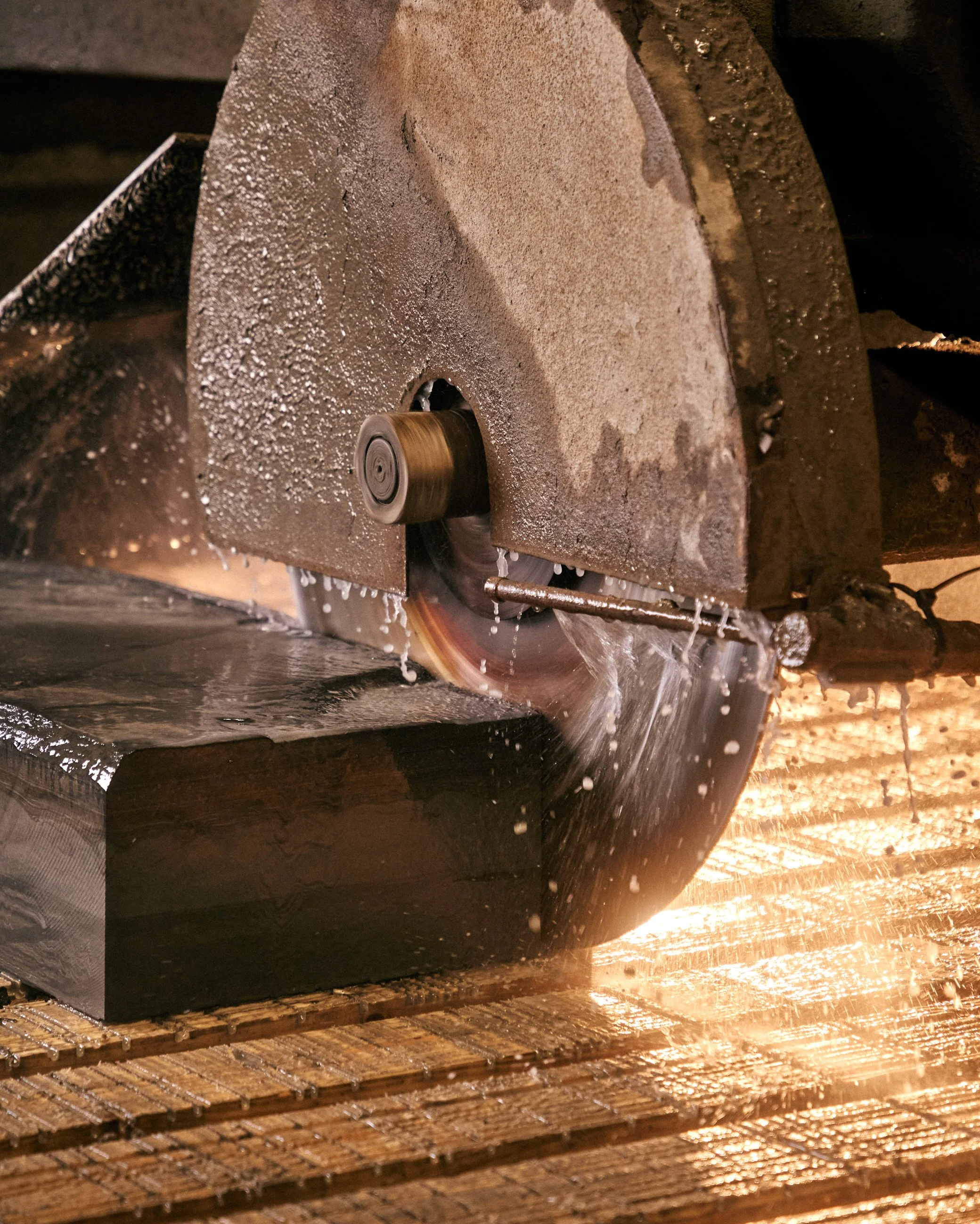Close-up view of a metal cutting saw against a glowing hot metal block, with sparks flying around during the cutting process.