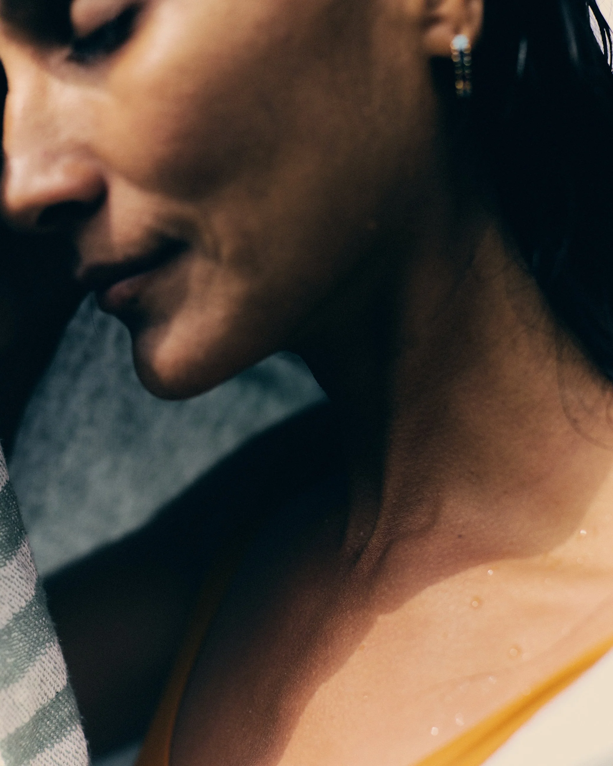 Close-up of a woman's face and neck, showing part of her shoulder and earrings.