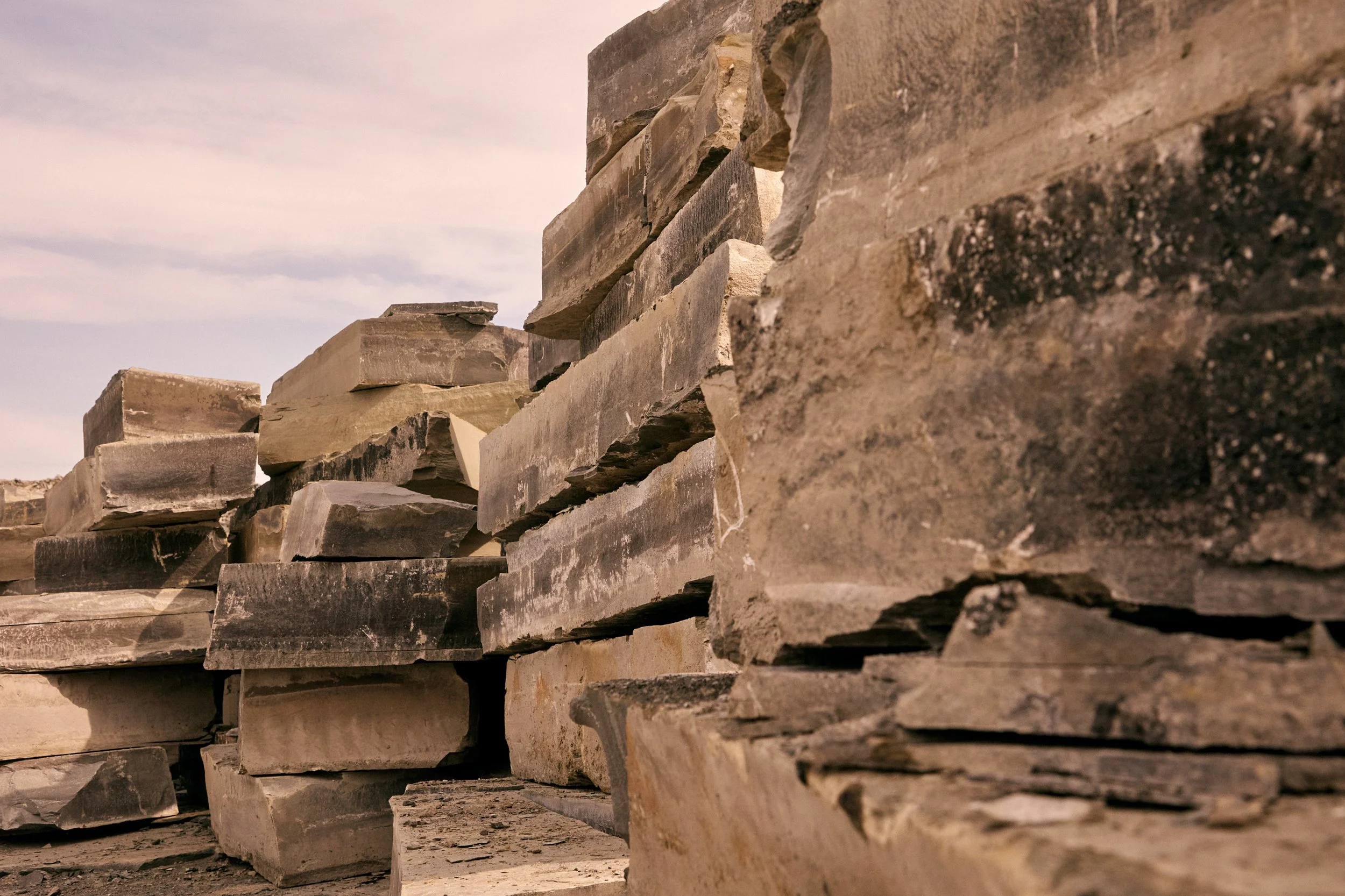 Stacked large flat stones forming a dry stone wall under a cloudy sky
