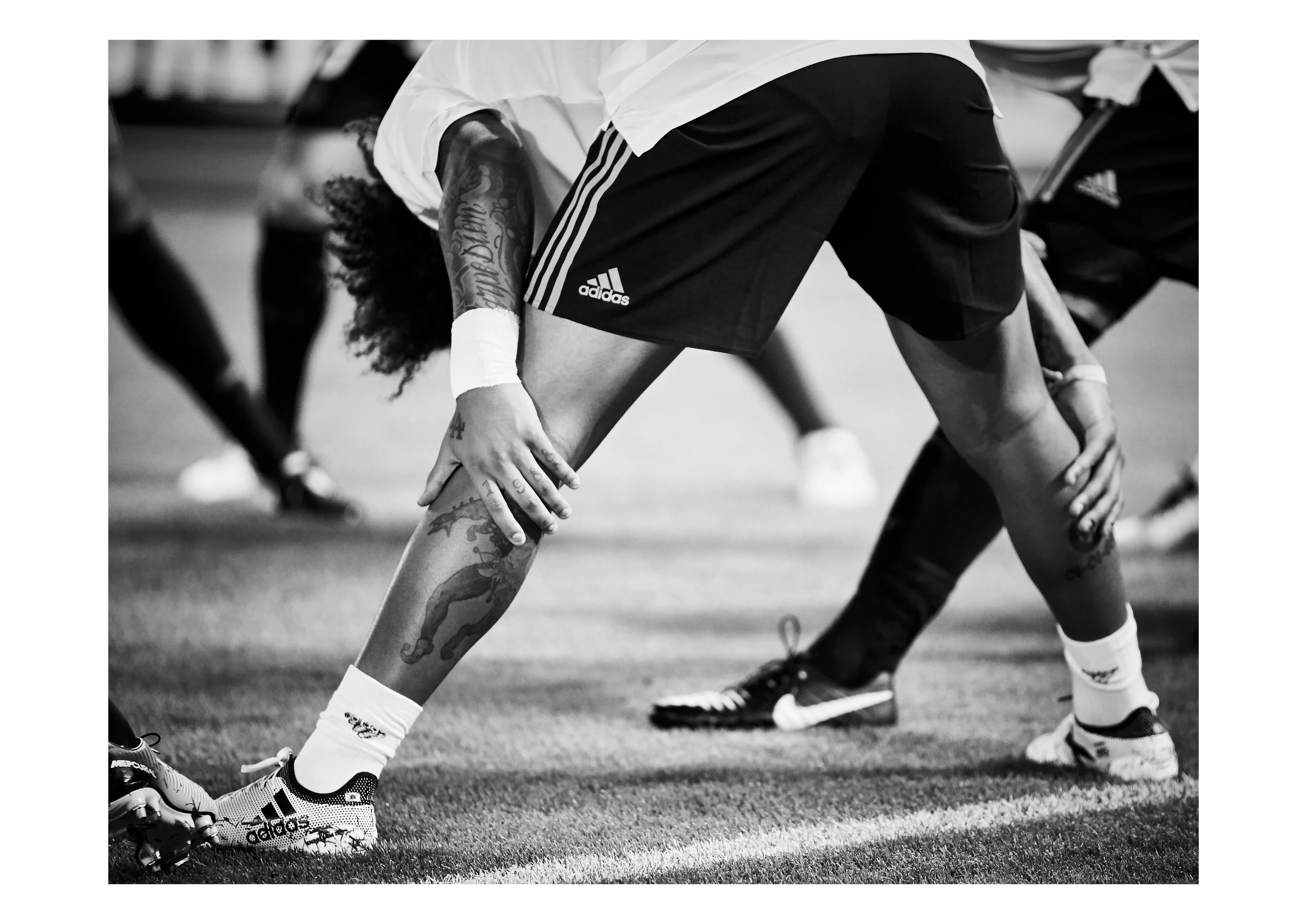Football players in a crouched stance preparing to line up for a play on the field, wearing athletic gear and cleats.