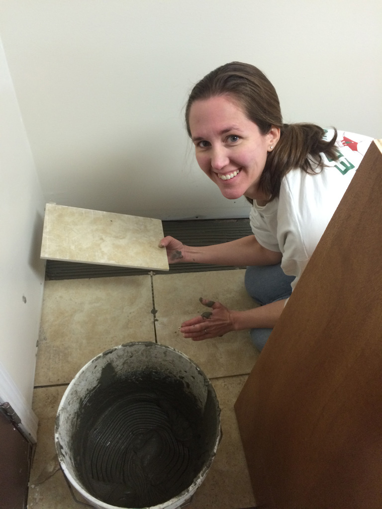 Jennifer setting tile. She thought it was good to "practice" on the area beneath the base cabinets first.