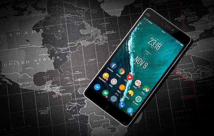 A smartphone displaying the time 23:18 and date November 9, resting on a world map background.