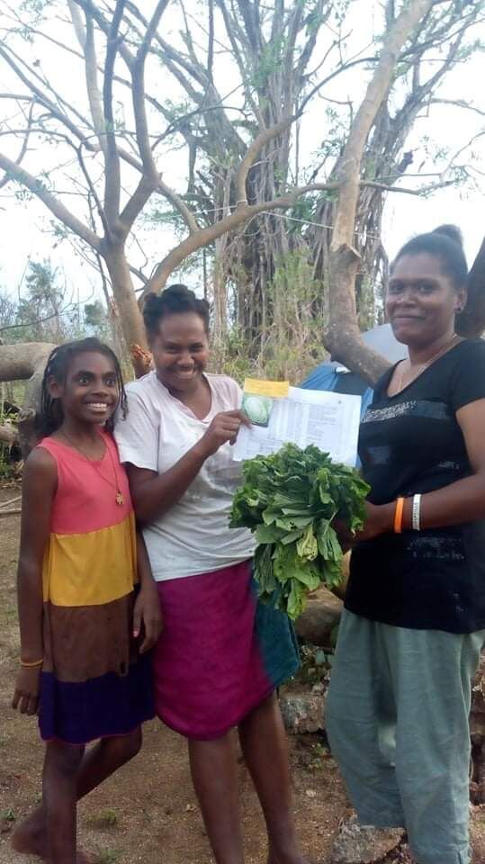  One of the team members of Friends of the Nation Youth handing over seeds and a seasonal calendar to a daughter and mother who have also lost their home during the cyclone. 