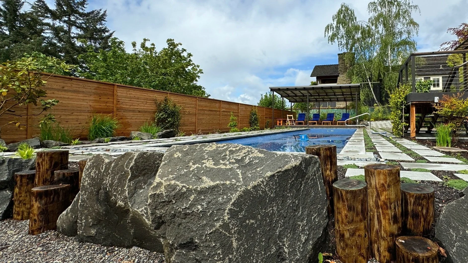 Wood pole retaining with black basalt boulders