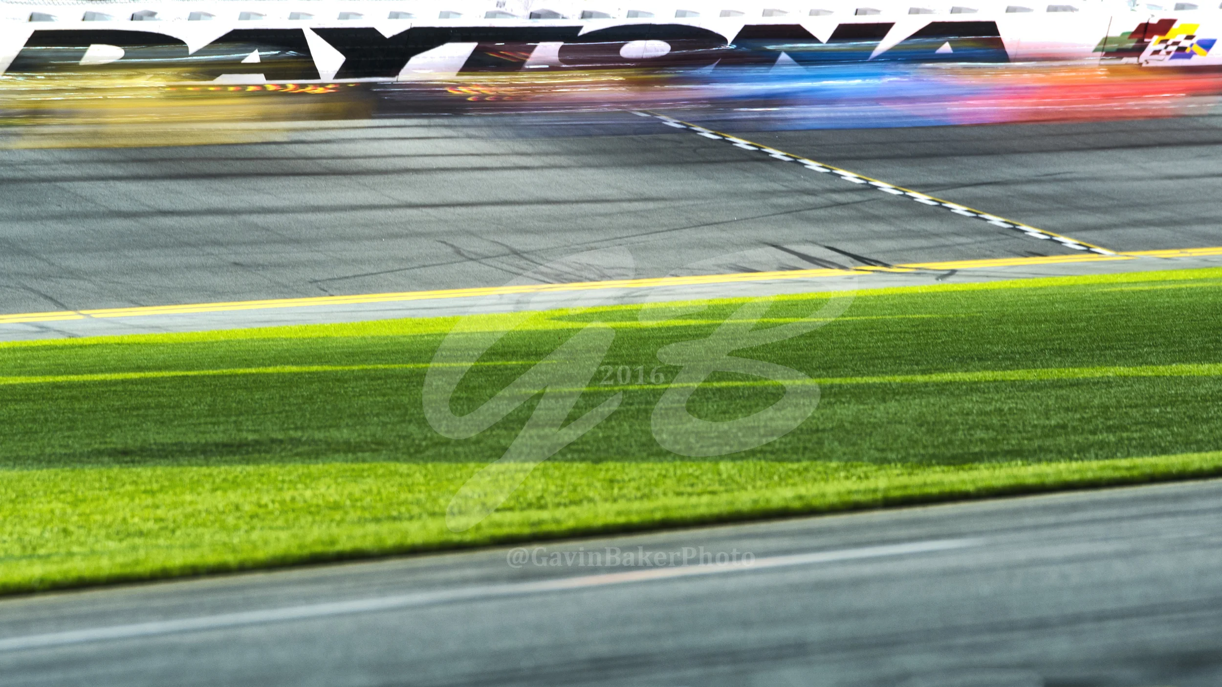 Sprint cars wiz by the Daytona sign crossing the start / finish line under the flag stand during one of the Can Am Duels