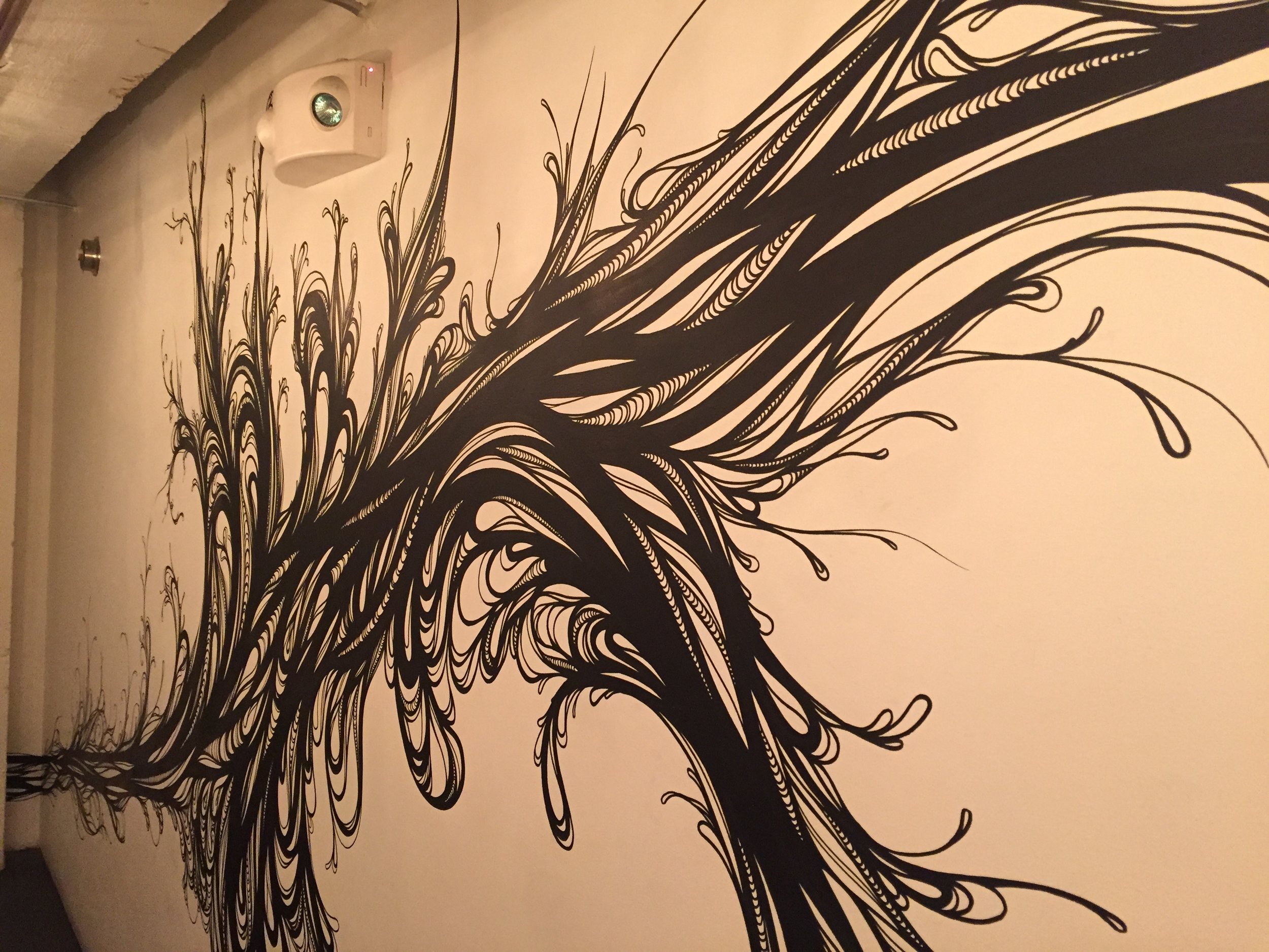 This project was commissioned by Timothy Felkner who opened up the short lived Oro restaurant during summer 2015 in Mint Plaza. The main motivation here was to create a sweeping piece of art that encapsulated all sides of a subterranean hallway which leads diners to the restrooms in the basement of the building. During the design phase I was struck that the work space was underneath the streets and buildings of San Francisco. I felt the power of being INSIDE the city. I was reminded of the 1906 earthquake and the energy that lies dormant underground. I thought of the nutrients in the Earth which gives rise to the food that grows from it. This two ideas harmonized and became the swirling sprouting mural that emerged. When I began this project the area had a dull, bland industrial feel with no life to it. Afterward, I created a one of a kind art piece which was an interpretation of what it's like for life to emerge from deep inside the city. 