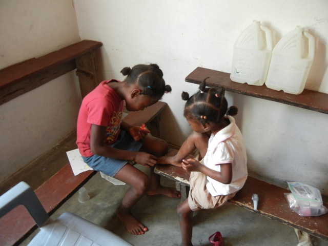 Haitian girls painting each other's toenails.