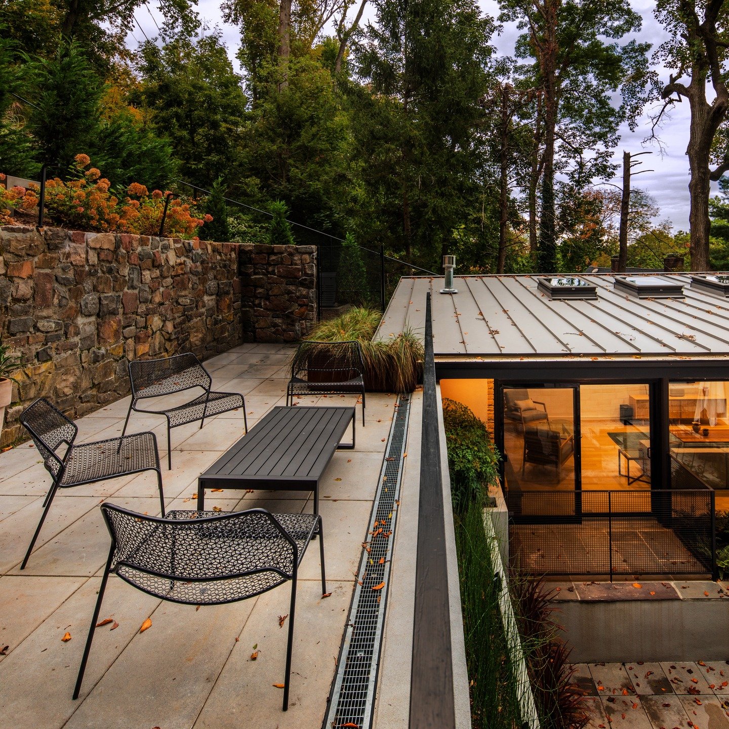 Quiet geometry, warm light, and just enough wildness at the edges.

This project plays with contrast: a grounded stone wall anchoring the site, a crisp metal roof floating above, and a sunken living space that pulls you gently into the landscape. The