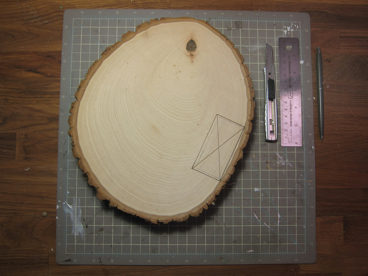 Position and center the battery pack of the LED lights on the bottom edge of the backside of basswood round. With a pencil, trace around the battery pack.