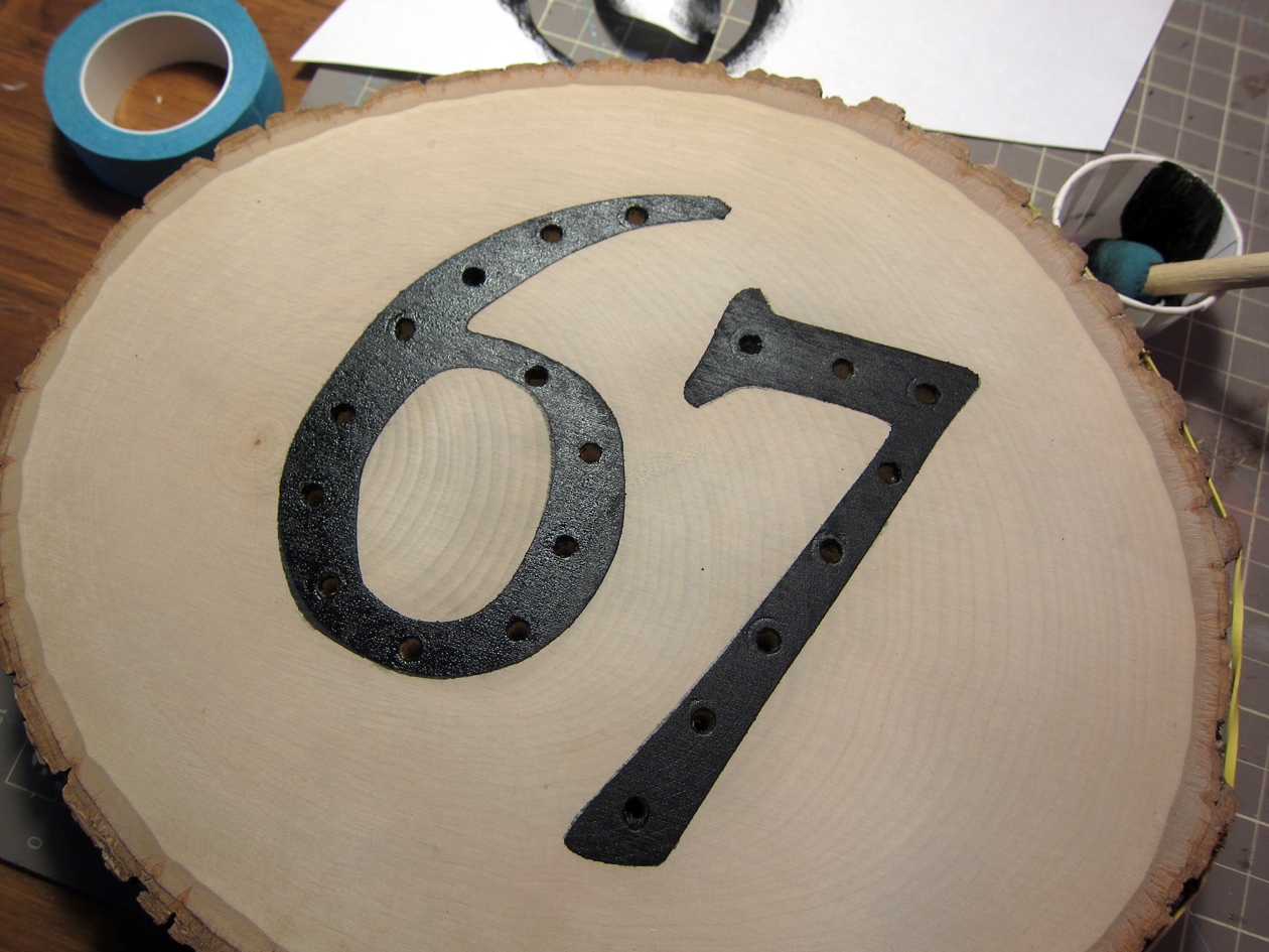 Clean off any wood dust and reapply number stencil. Touch up paint in and around drill holes. Let dry.