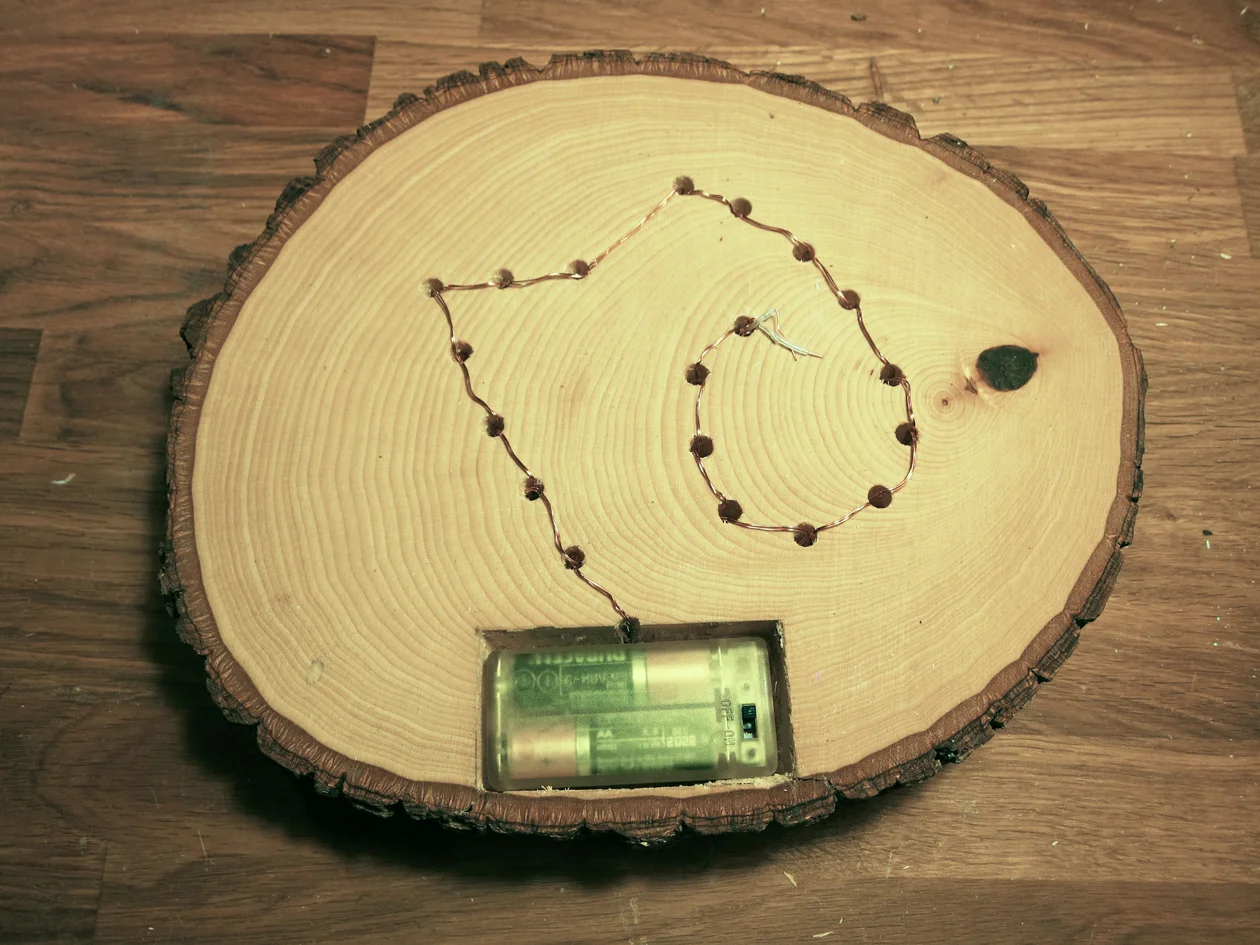 Flip Basswood round over. Place battery pack into place. Insert a light into each drill hole. Secure in place with tape.