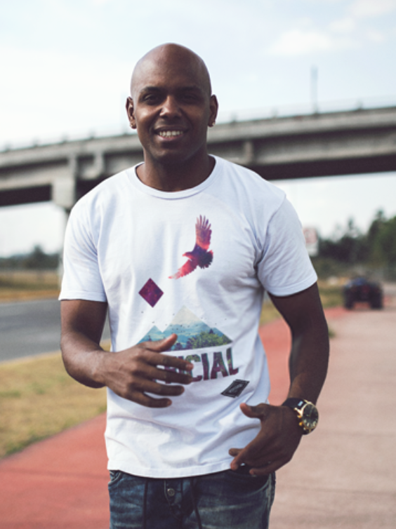 Bald Black Man Smiling While Wearing a Round Neck Tee in a Quiet StreetMNKSO.png