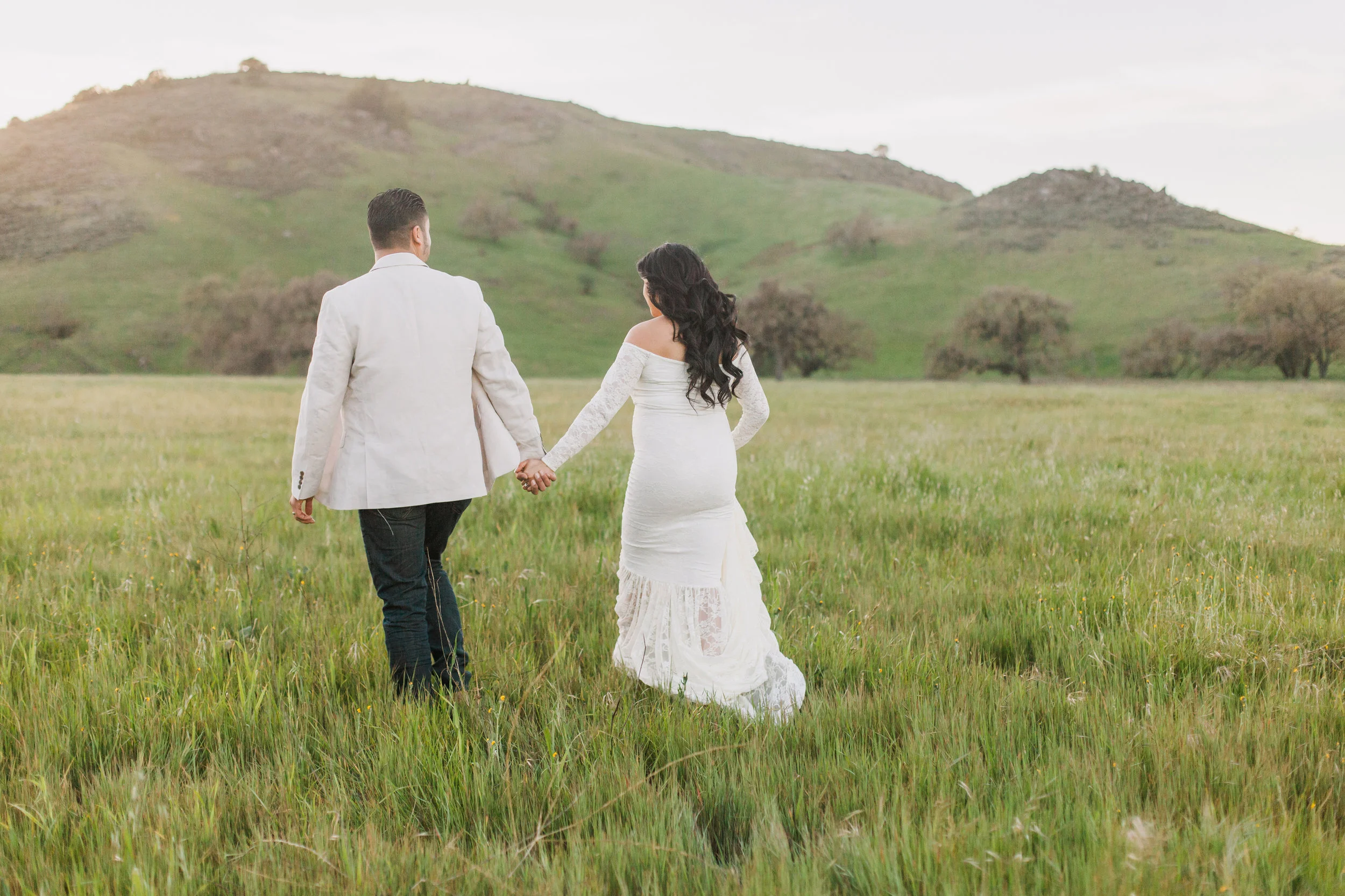 Couple walking in a grass field wearing during maternity session in San Jose, California.