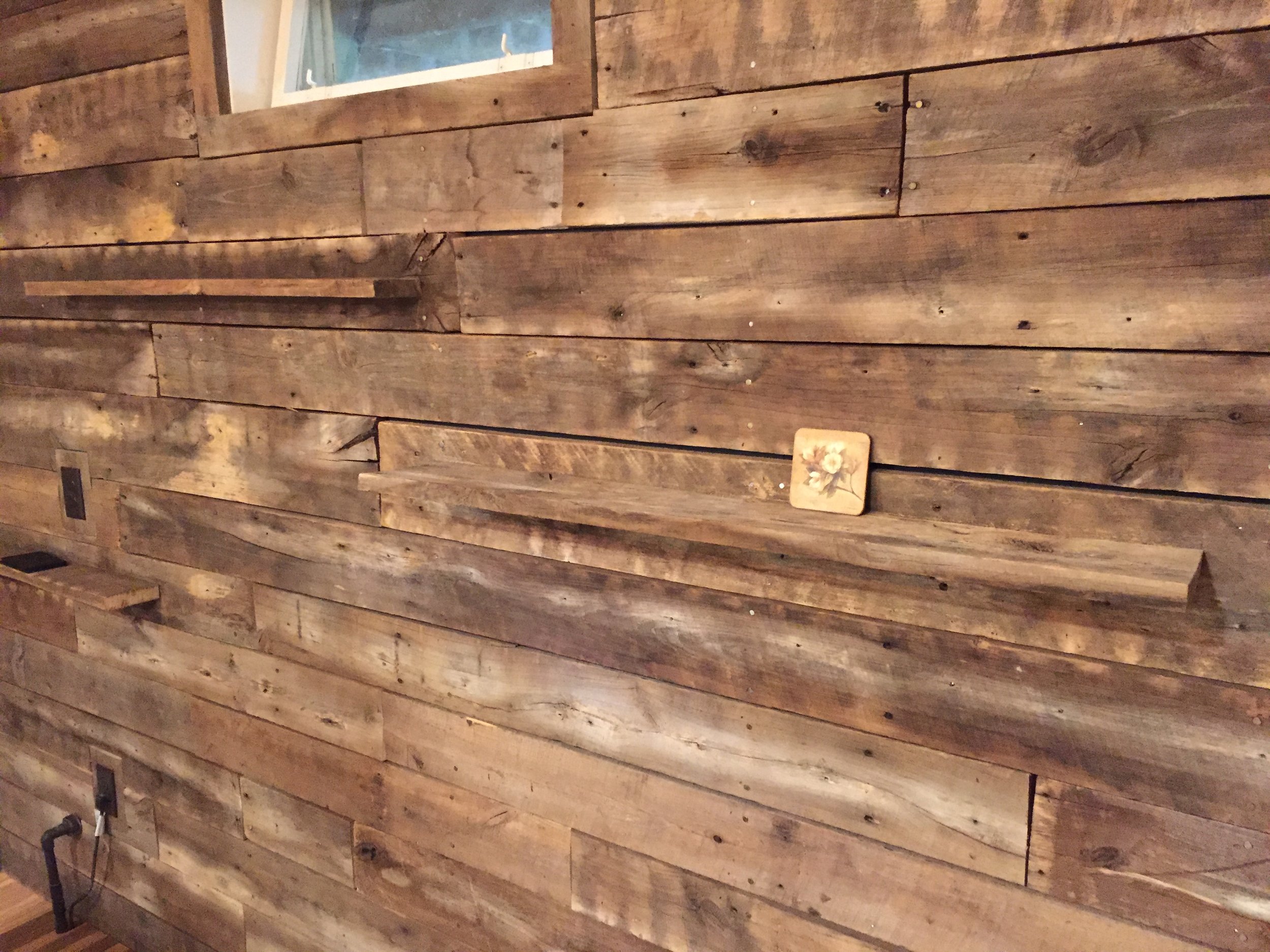  The back wall of the bar corner was sided in reclaimed barnwood. The crew carefully selected boards with nail holes to the give the wall more character. Some boards were turned on their side to create floating shelves. 