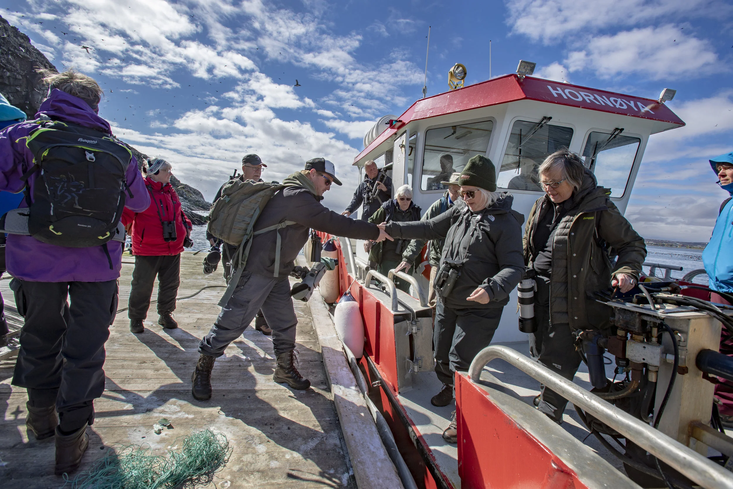 TURGRUPPER: Vardø Havnevesens båt er stor og stødig, noe mange eldre turister setter pris på. Anders Mæland hjelper sin utenlandske turgruppe på land.