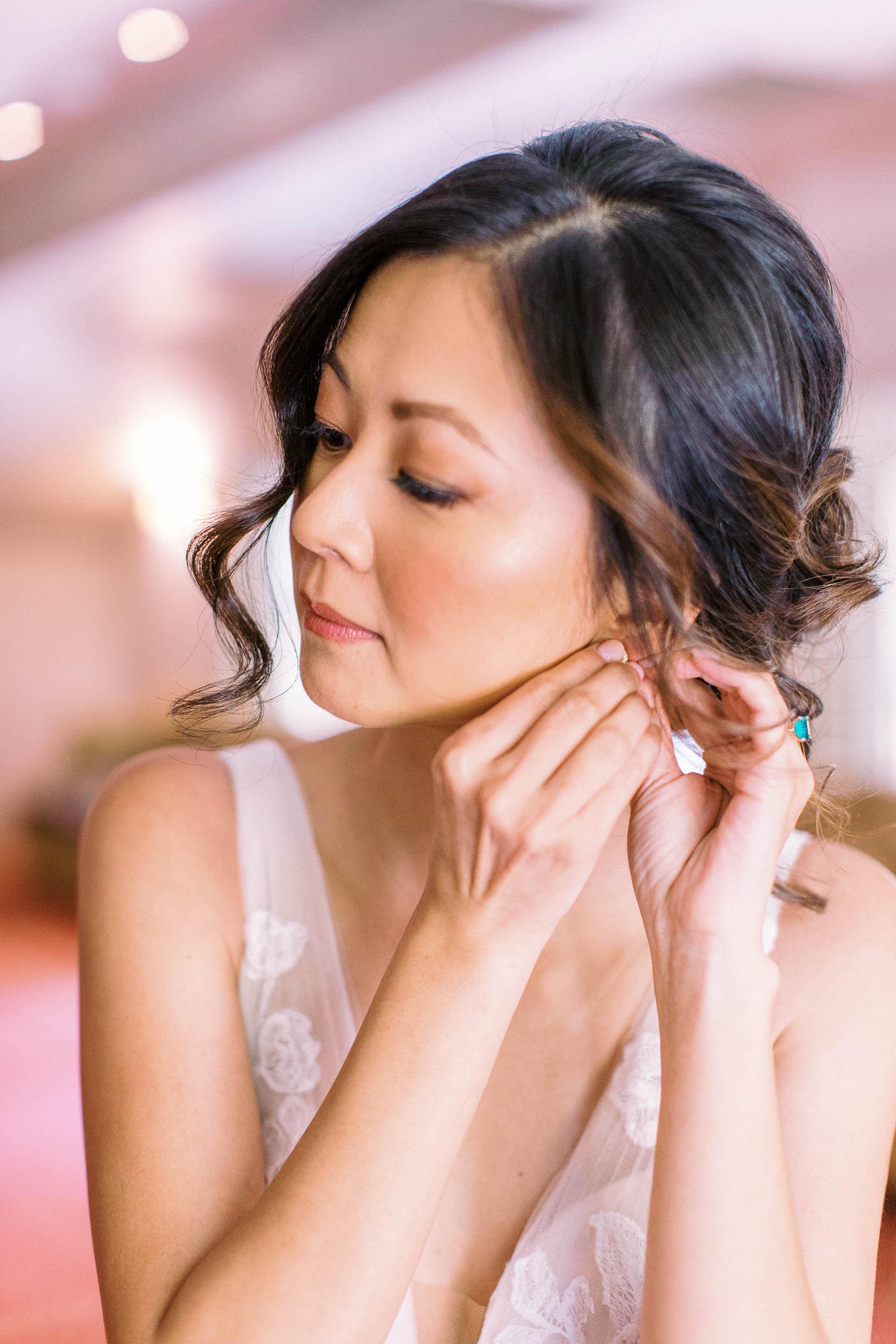 bride putting on earring at wedding