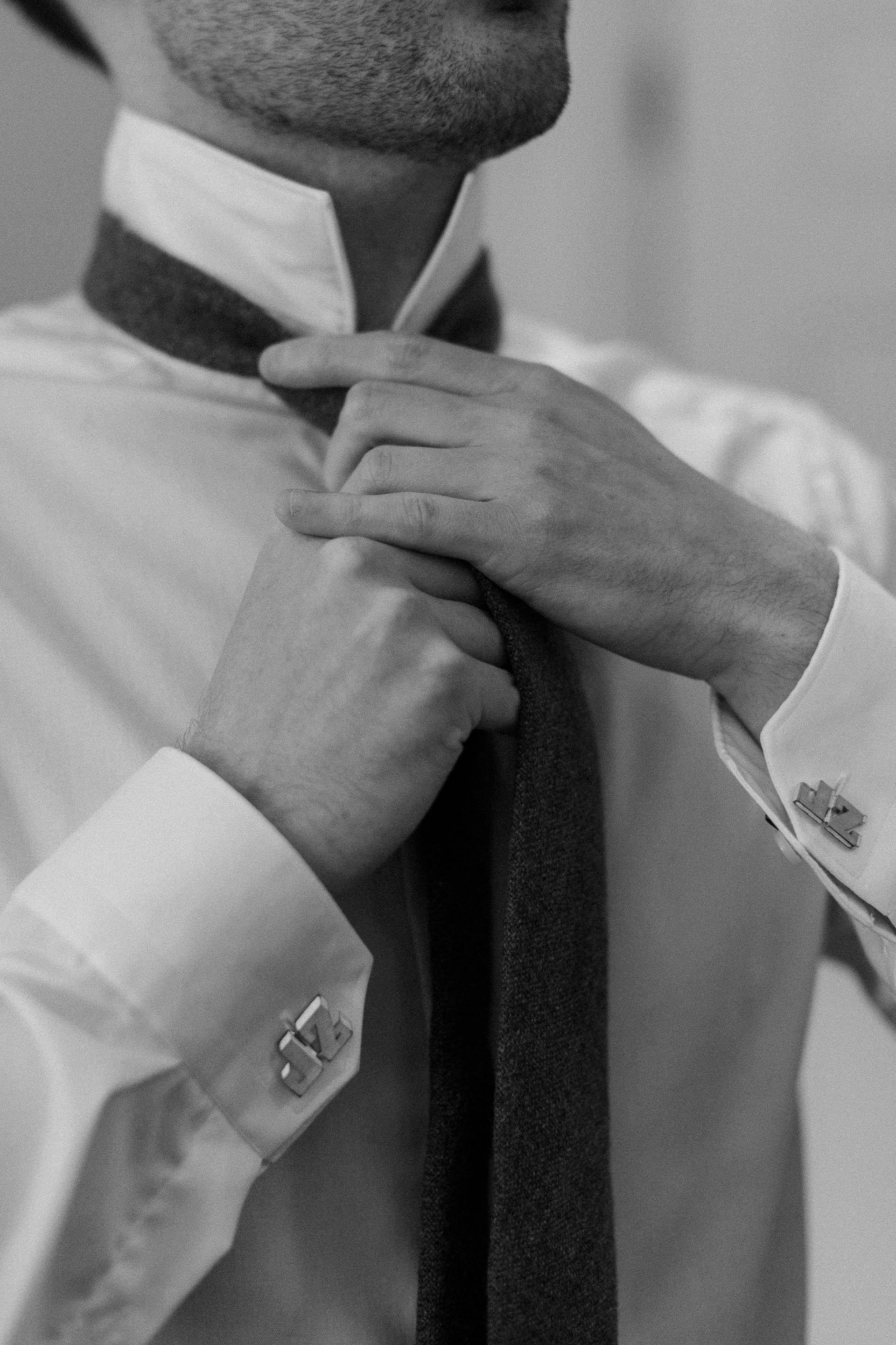 groom putting on tie at wedding