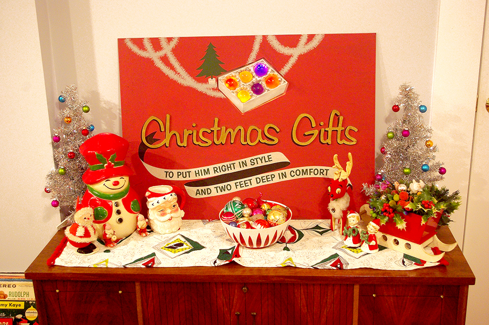 One of my vintage Christmas displays. The sign is one that my brother Tommy got for me. It is an old advertising sign, from a 1950s/1960s men's clothing store in North Carolina. I wound LED lights behind the sign, to light up the Christmas bulbs.