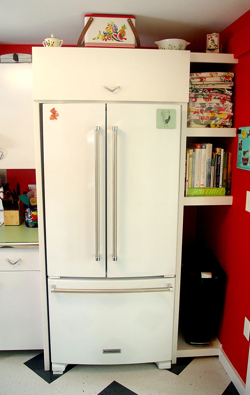 Custom fridge surround with tall appliance shelves and trash can storage.