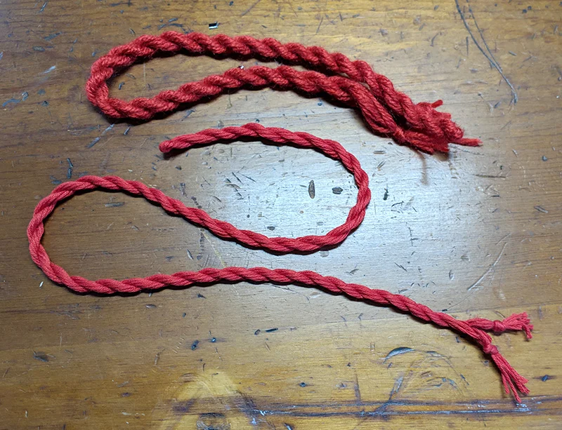 The top cord is made with yarn and the bottom cord with embroidery thread.