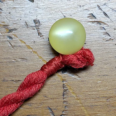 The knotted end of the cord with ball button attached.