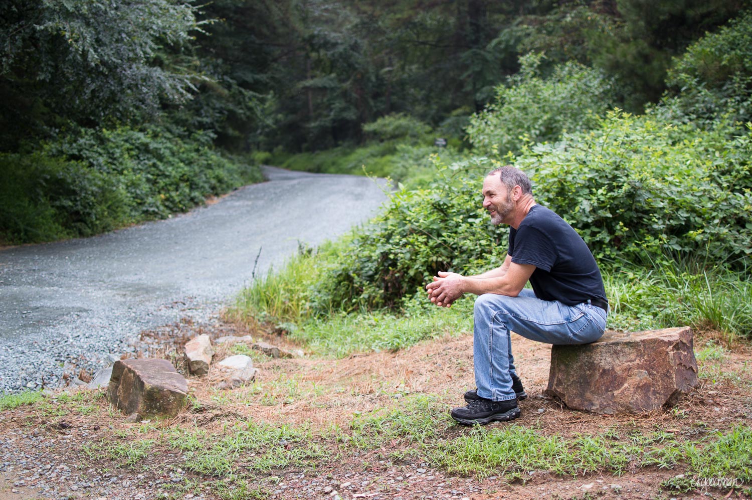 My dad pauses for a break on a rock by the gravel trail.