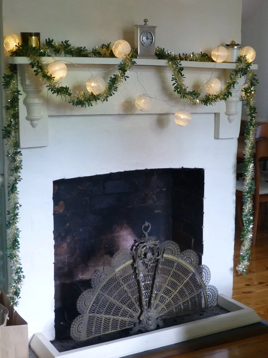 The mantlepiece is decked out in tinsel and fairy lanterns. 