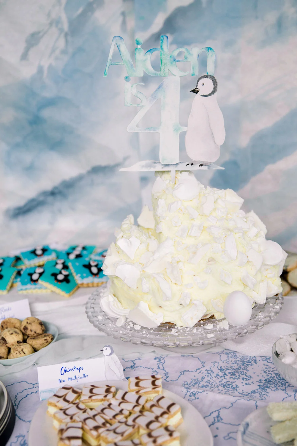 An "iceberg" cake was made for the central birthday cake, shards of meringue embedded in the frosting were used to indicate ice and the custom cake topper represented the penguin. 