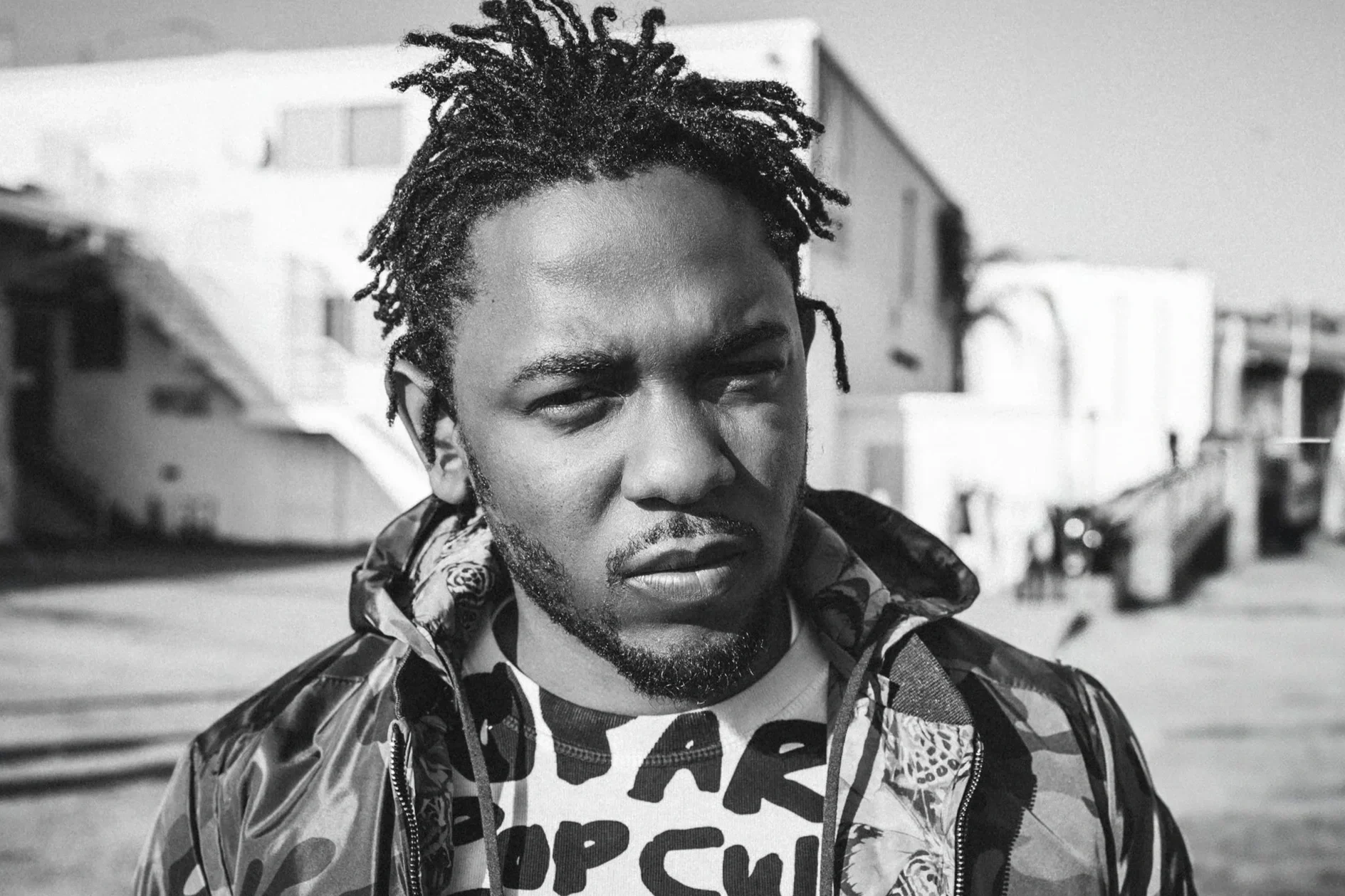 A young man wearing a baseball cap with the Los Angeles Dodgers logo sitting in the driver's seat of a vintage car, looking out the window.