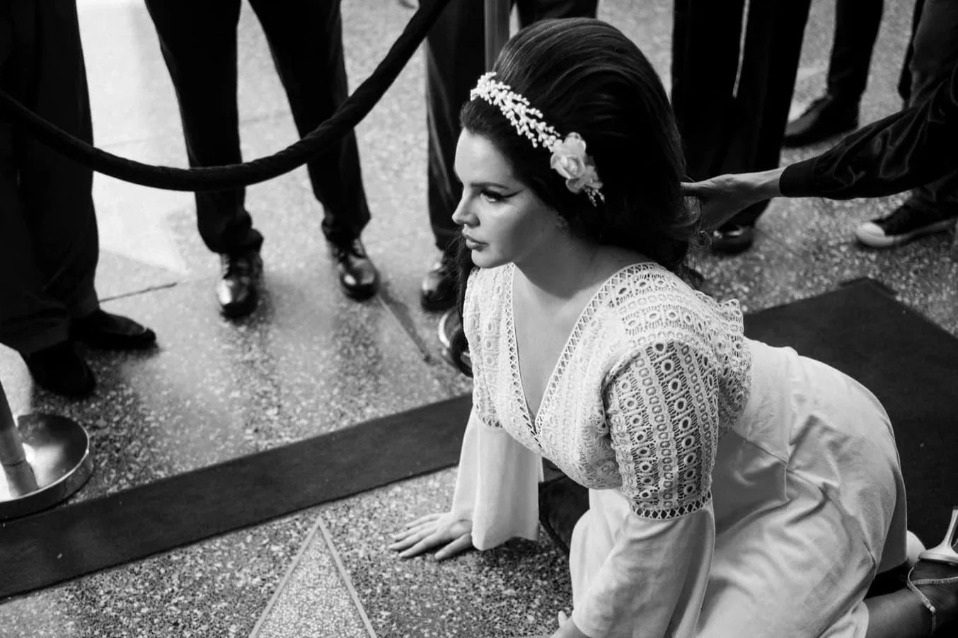 Black and white photo of a woman sitting alone in the backseat of a vehicle, looking out the window with rain visible on the glass.